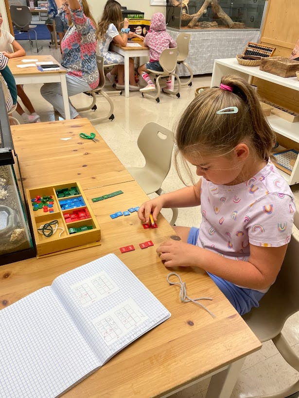 Child working with colorful blocks at a table in a classroom