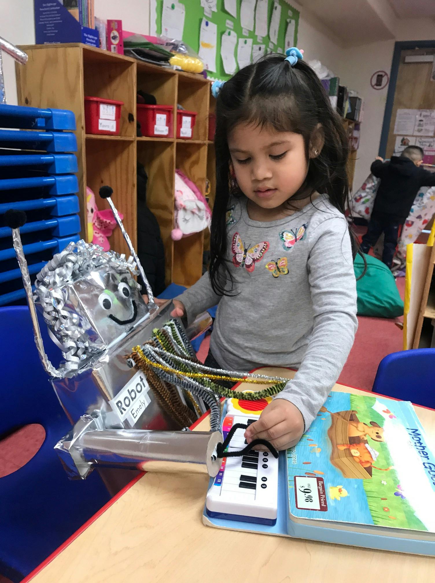 Child playing with a robot toy and a book with a small keyboard attached