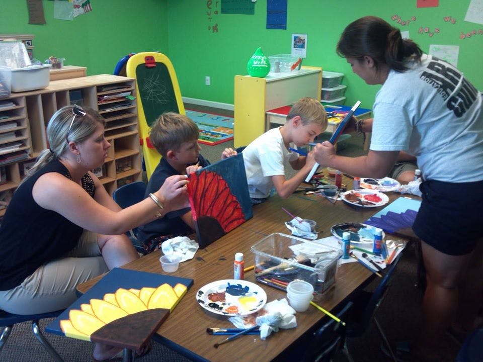 Adults and children painting at a table