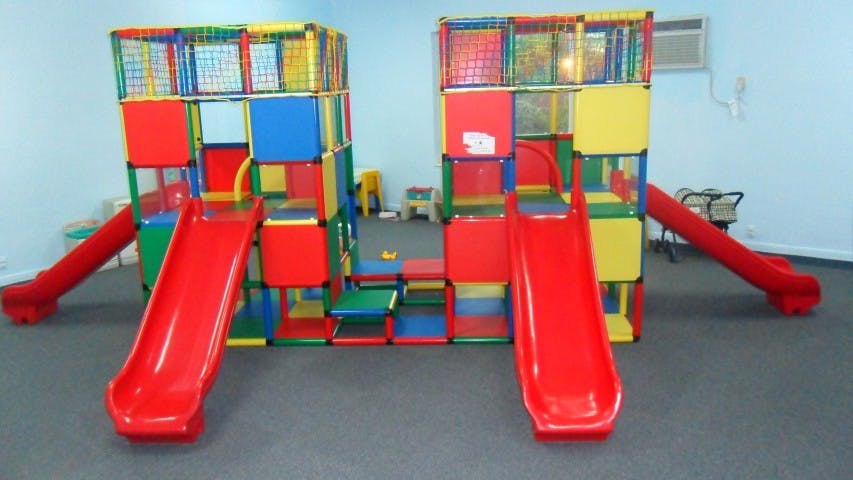 Indoor playground with two red slides and colorful climbing structures