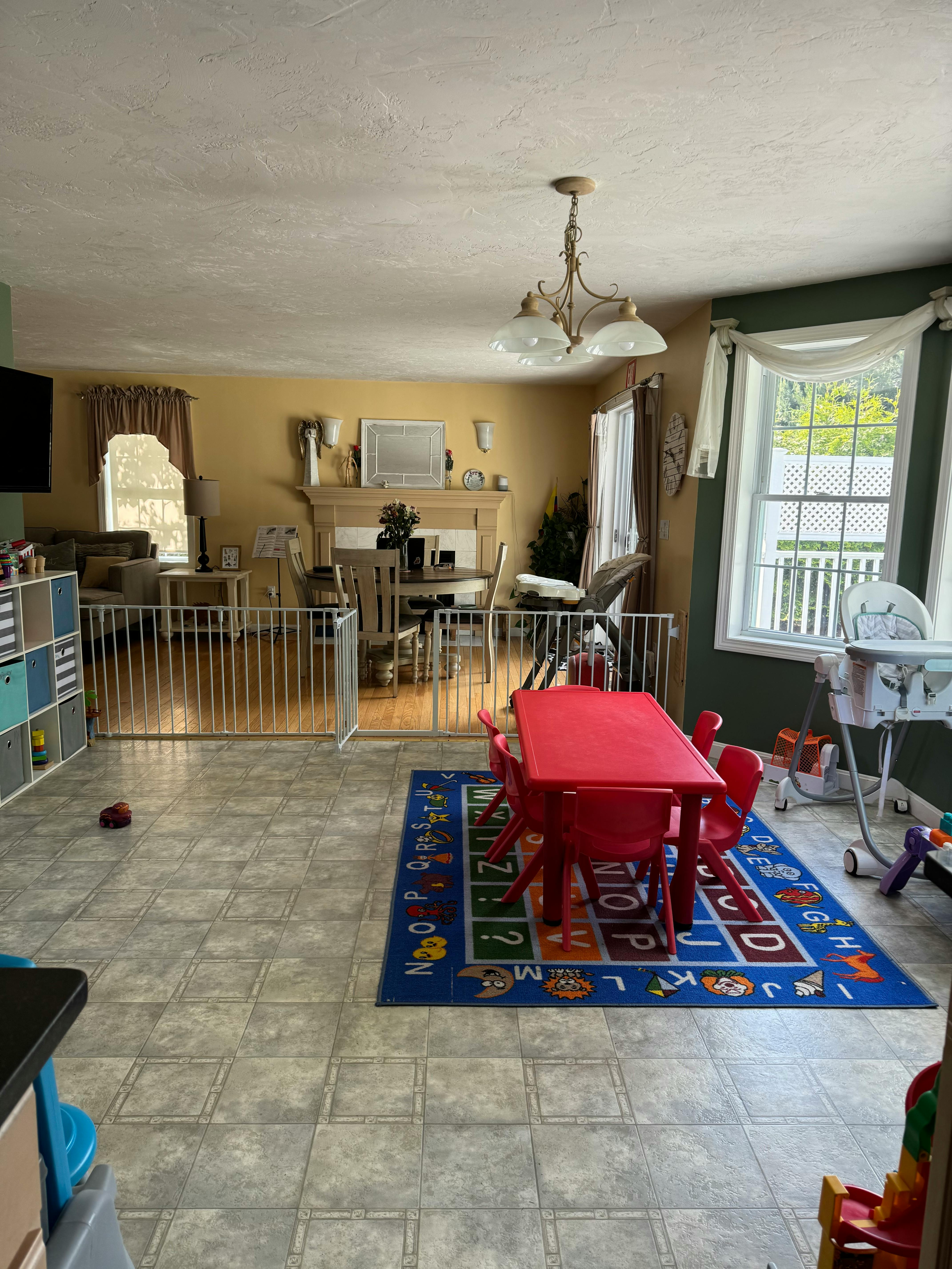 Living room with baby gates, a red children's table, and an alphabet rug