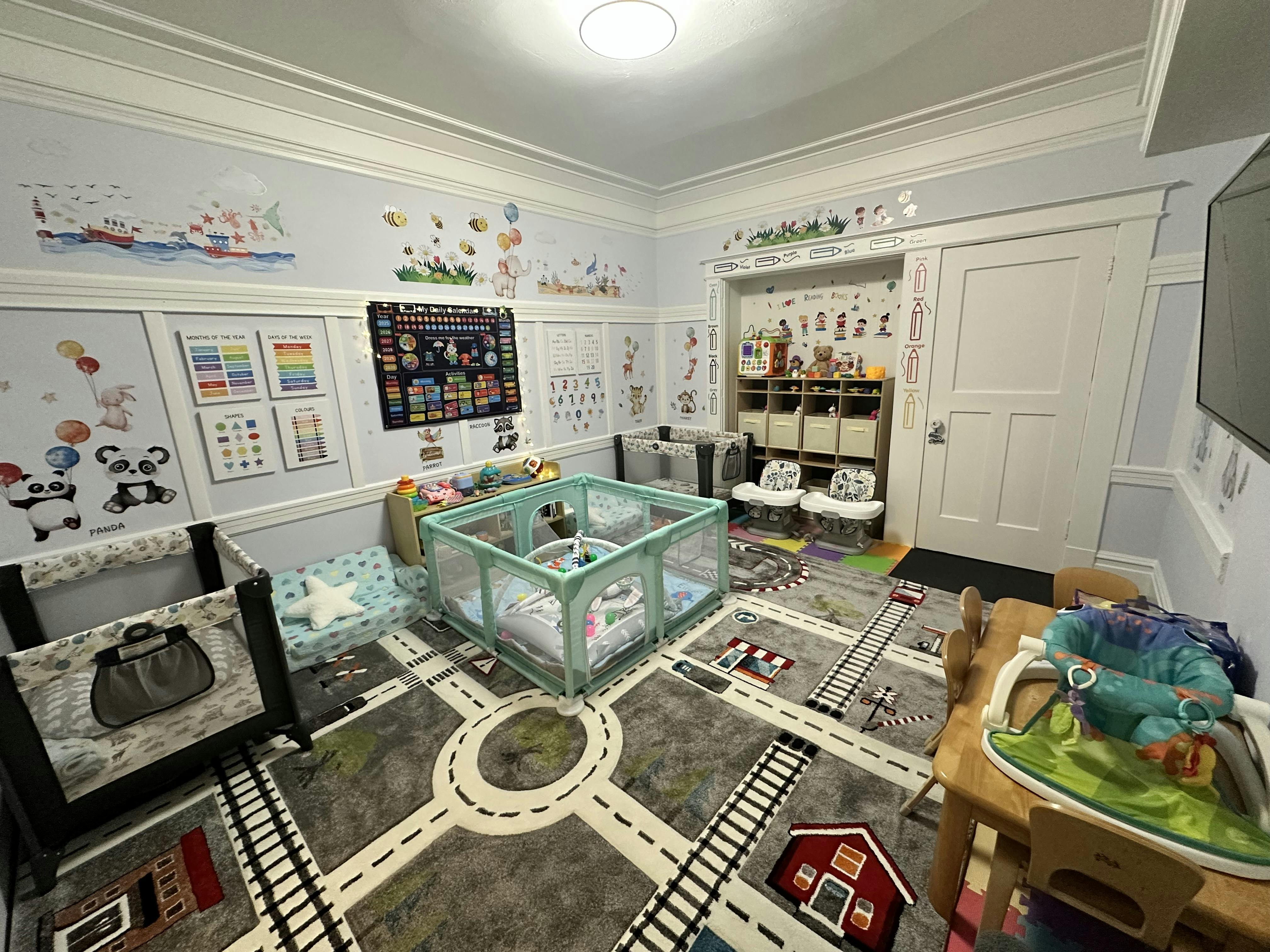 Playroom with cribs, playpen, and road map rug