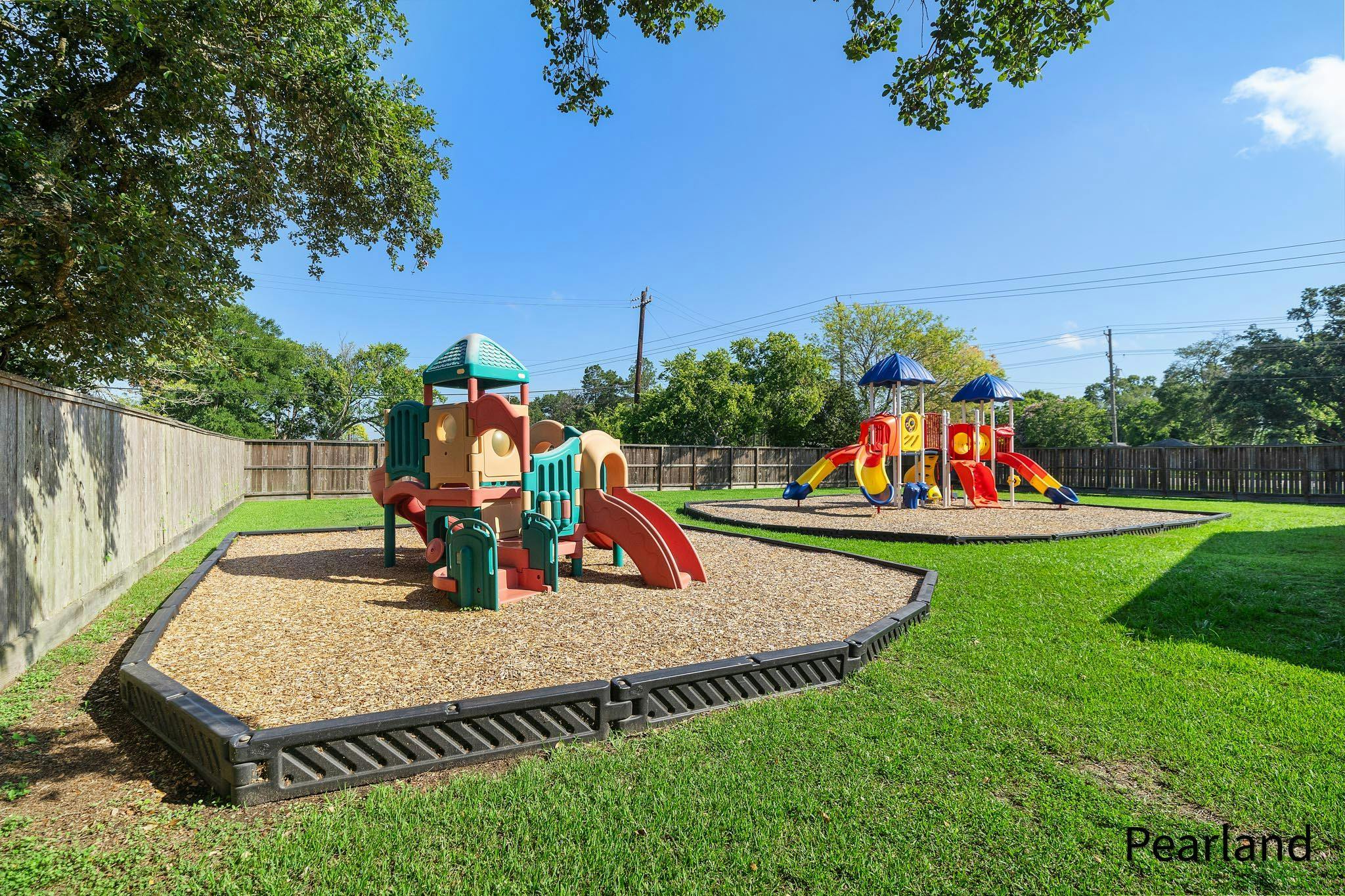 Two playgrounds with slides and climbing structures on wood chips