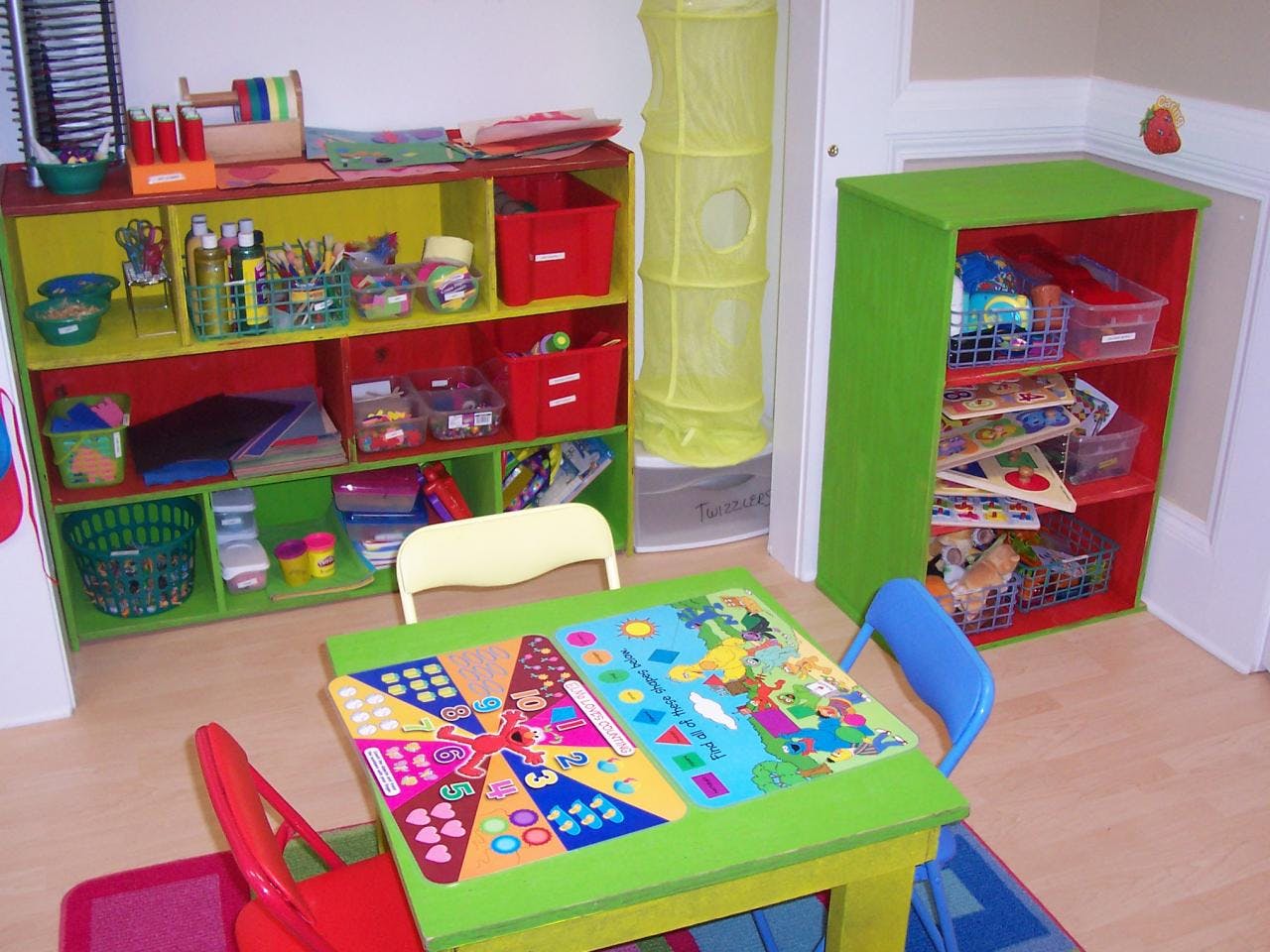 Playroom with colorful shelves, a small table, and chairs