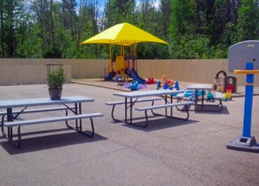 Outdoor play area with picnic tables, playground, and basketball hoop