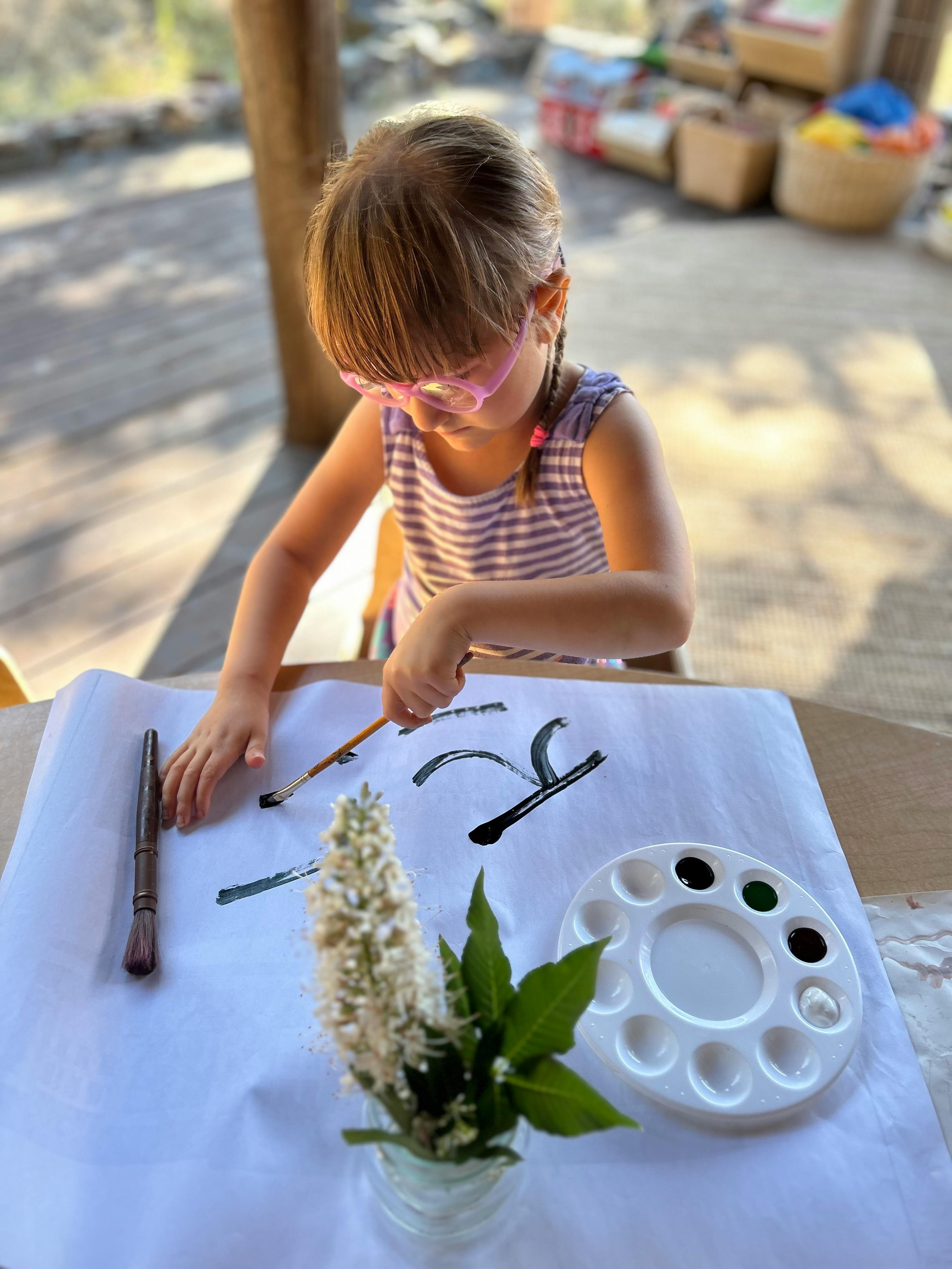 Child painting on paper with a paintbrush