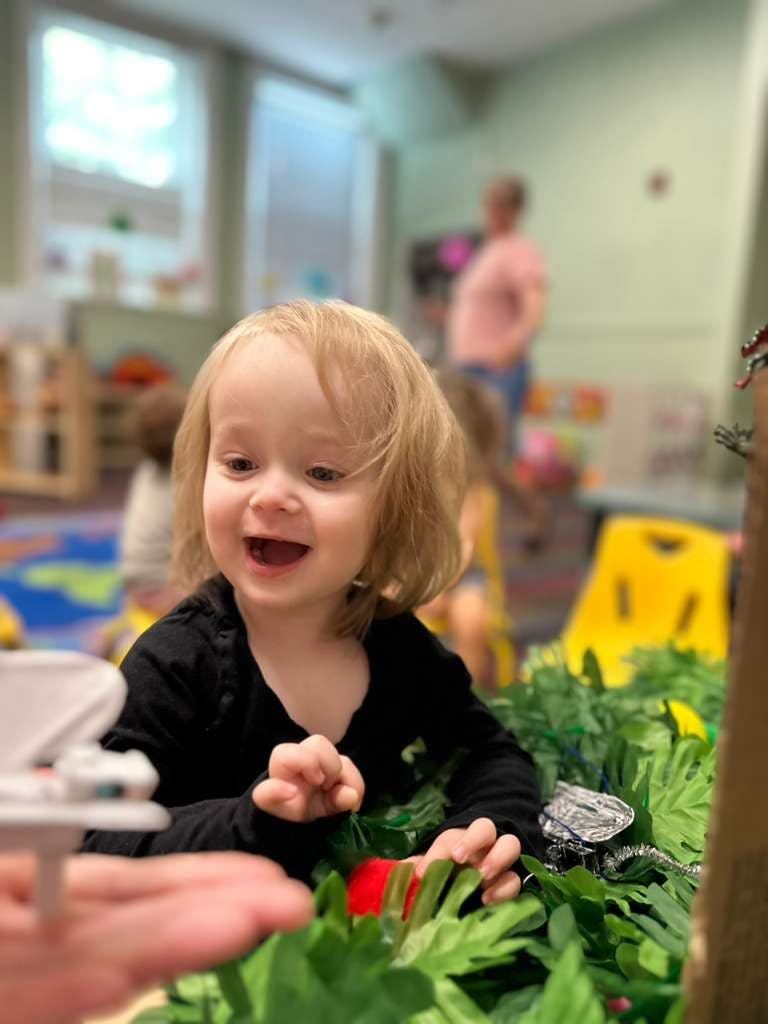 Child reaching toward an object in a classroom setting