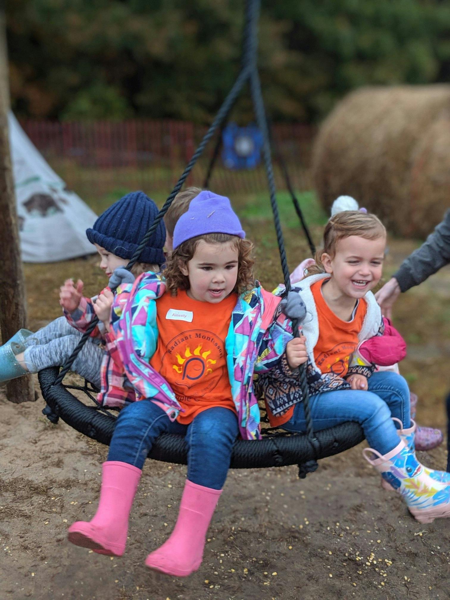 Three children sitting on a round swing