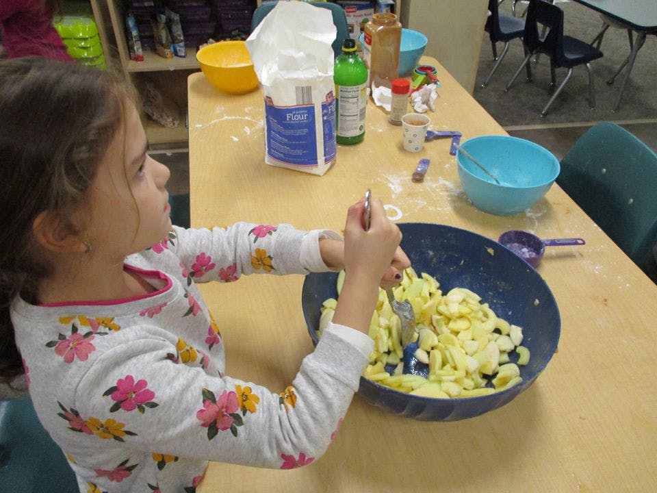 Child mixing food in a bowl with a fork