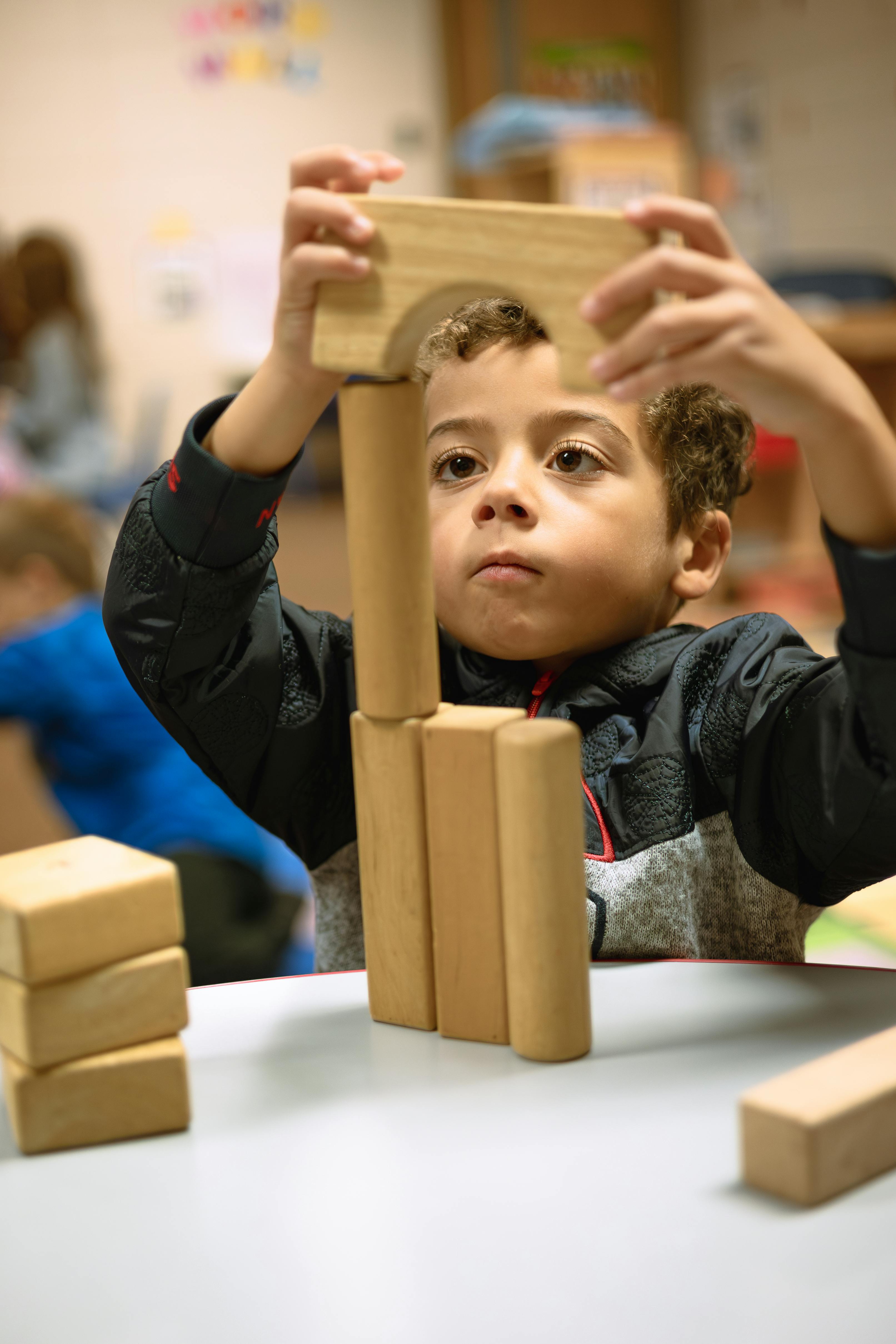Child building a structure with wooden blocks at a table