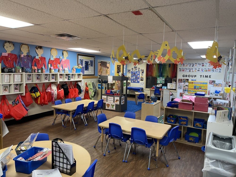 An empty classroom with small tables and chairs, and art on the walls