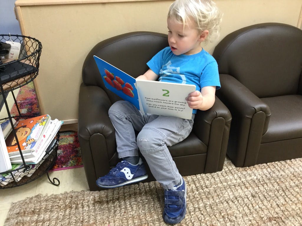Child sitting in a chair reading a book