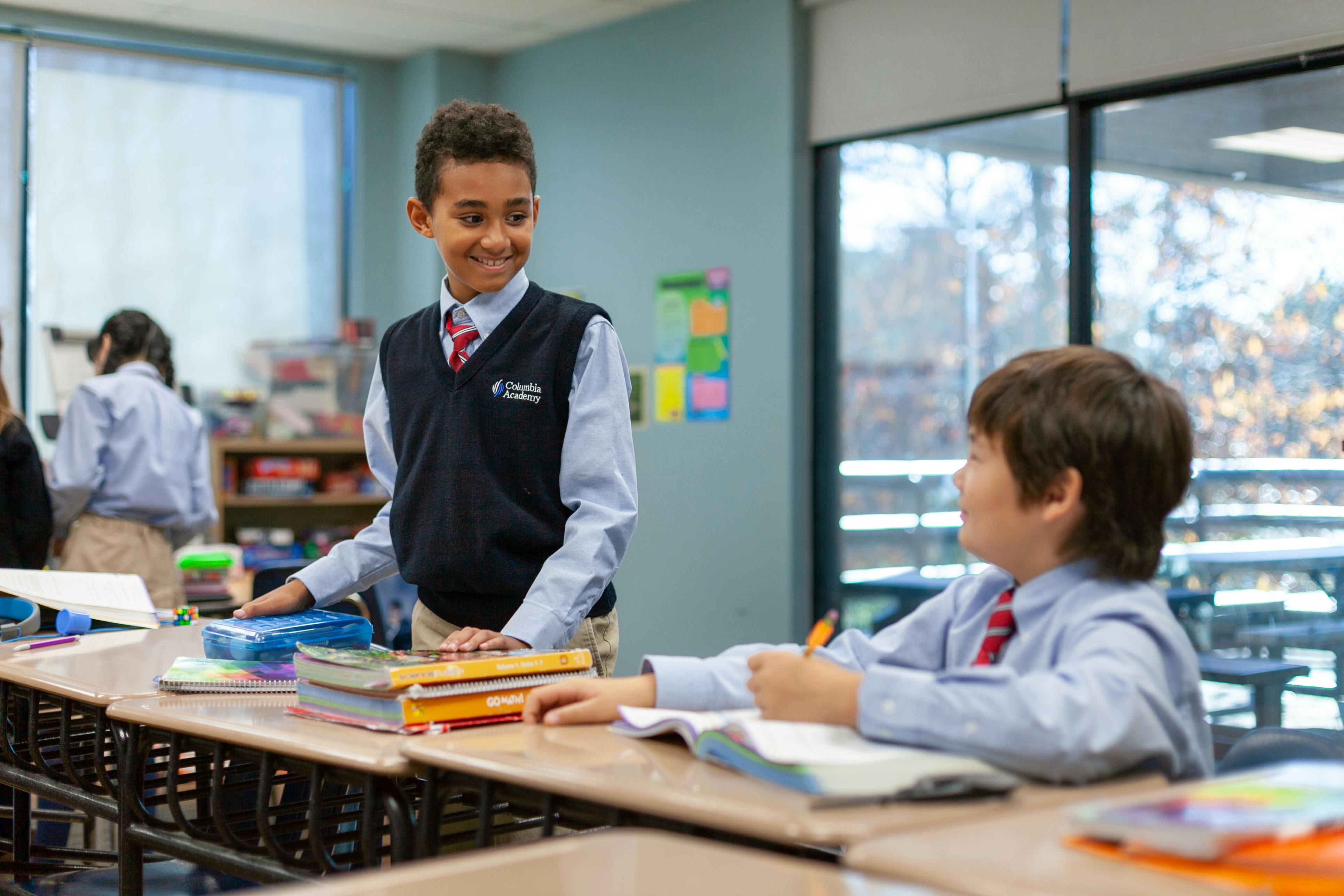 Two children in uniform at desks in a classroom