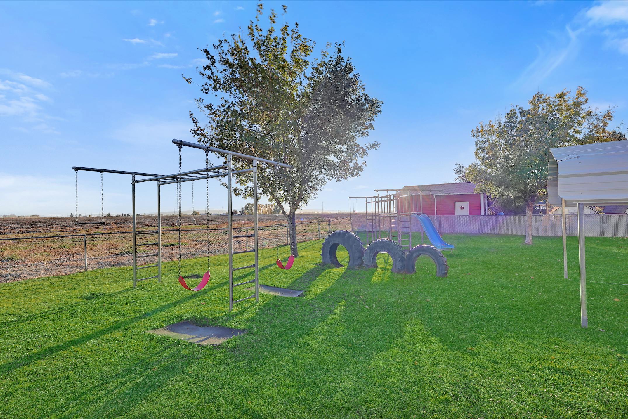 Outdoor playground with swings, monkey bars, and tire structures on green grass