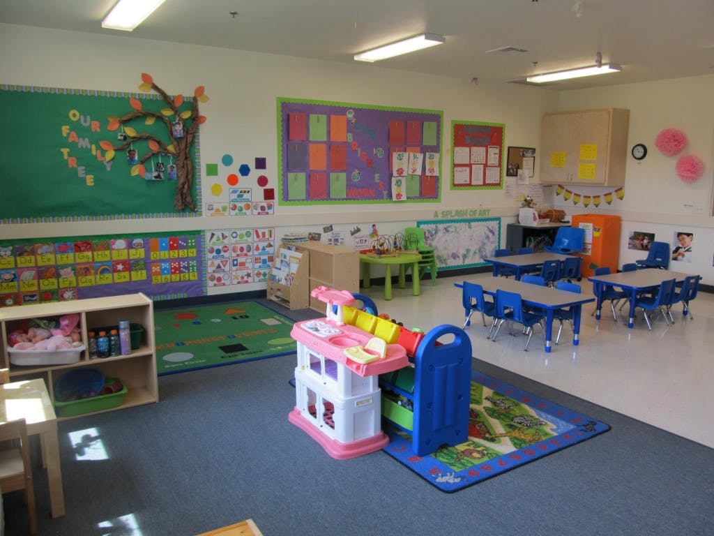 Empty classroom with small tables and chairs, colorful decorations on walls