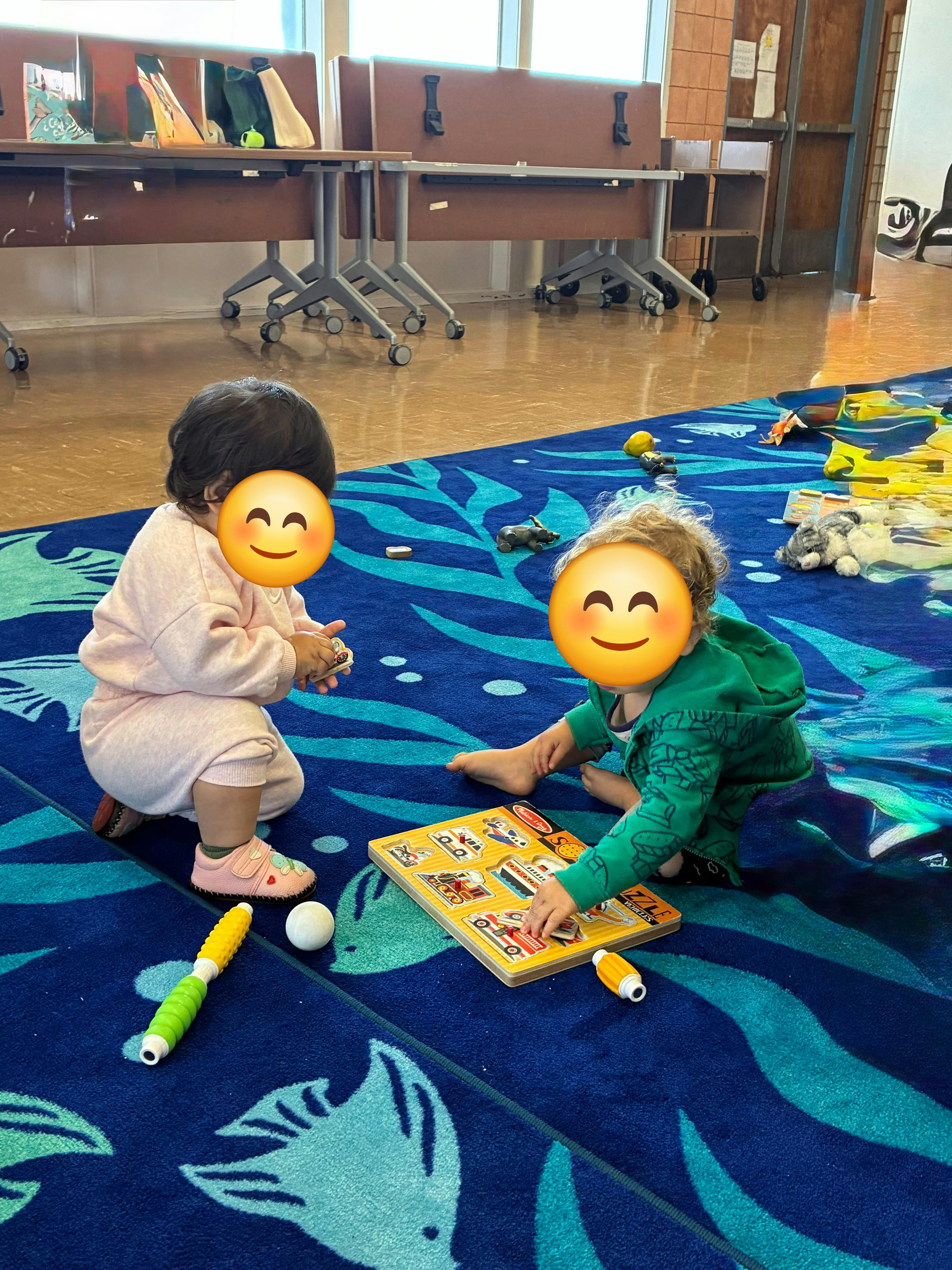Two children sitting on a patterned blue rug playing with a wooden puzzle