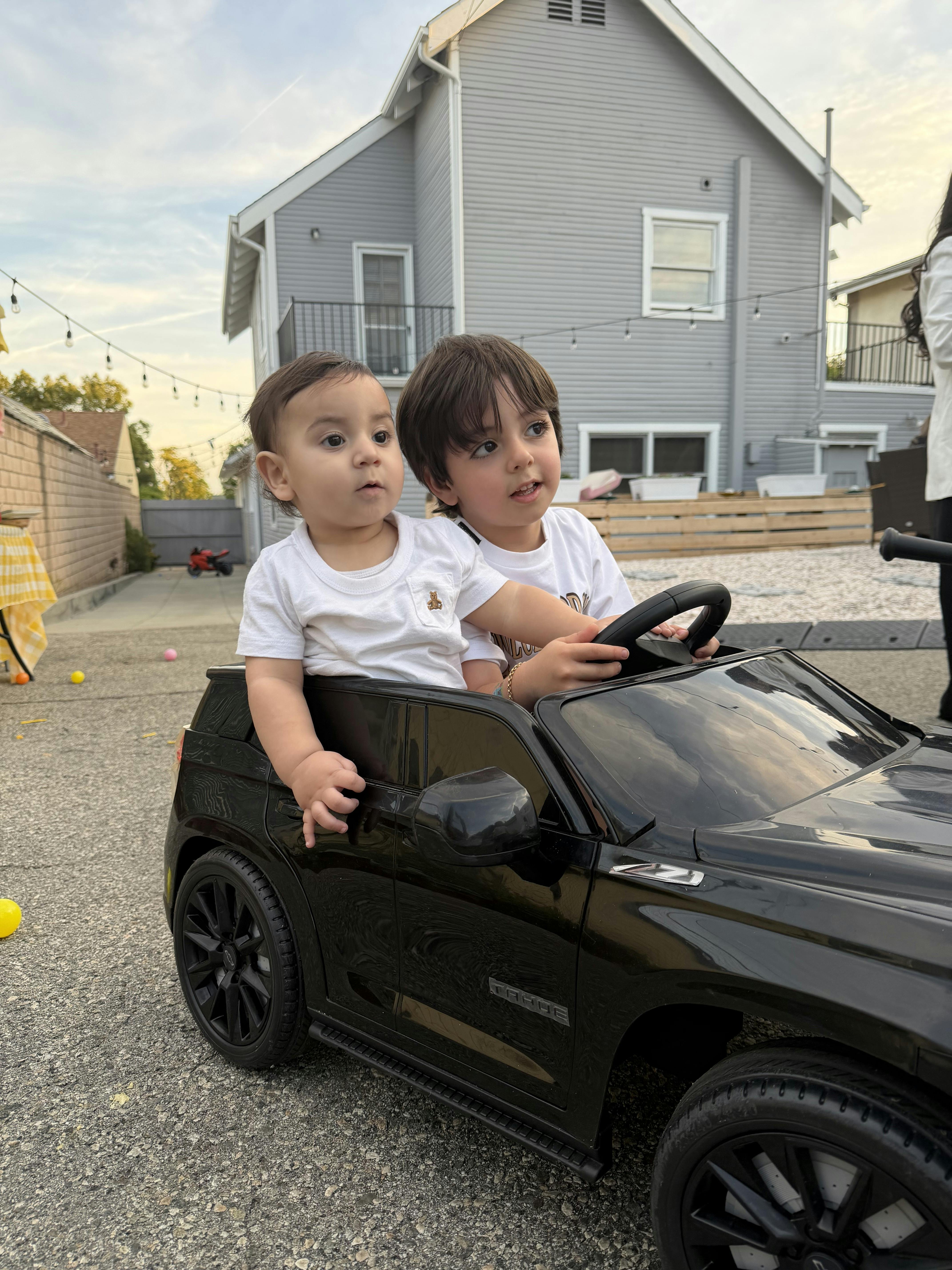 Two children in a black toy car