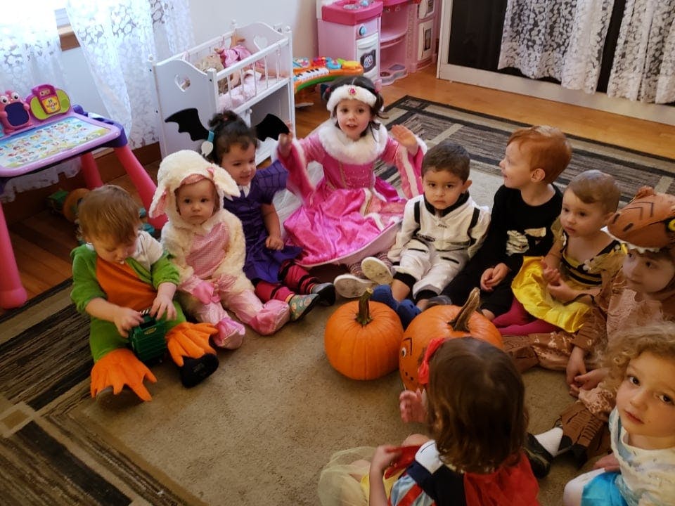 Children in costumes sitting in a circle with pumpkins