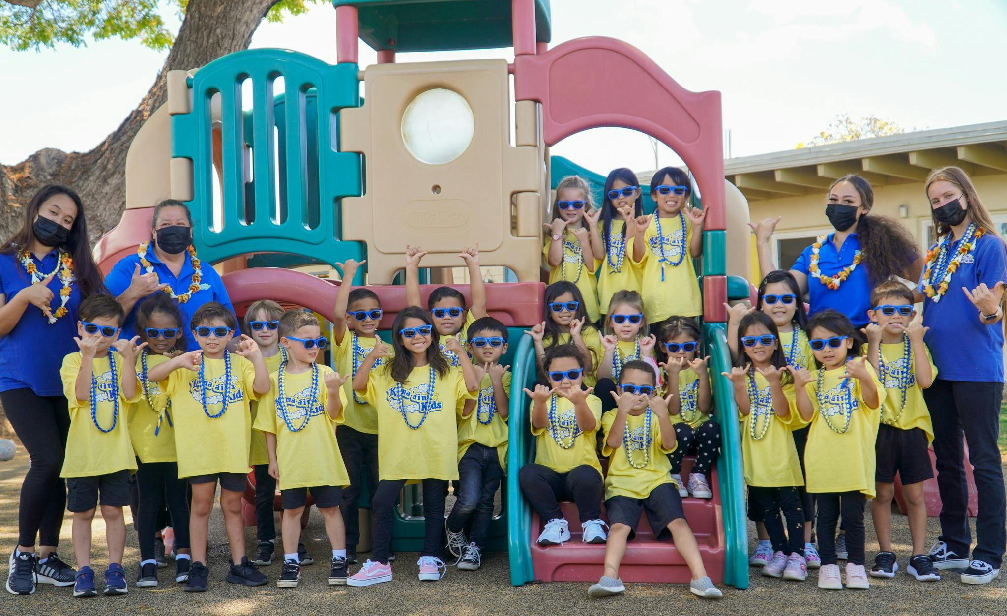 Adults and children in yellow shirts and sunglasses posing on a playground