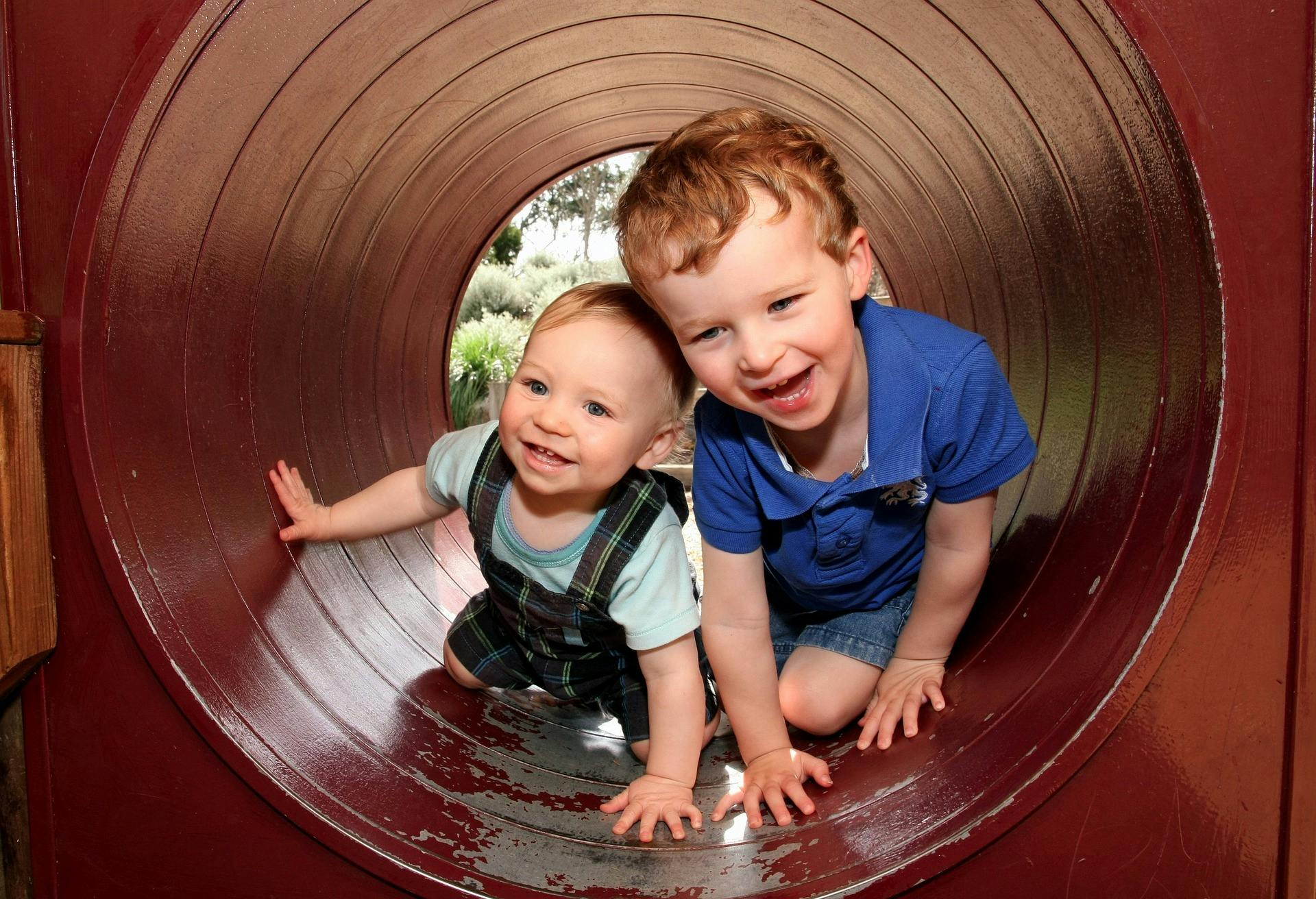 Two children crawling in a tunnel on a playground