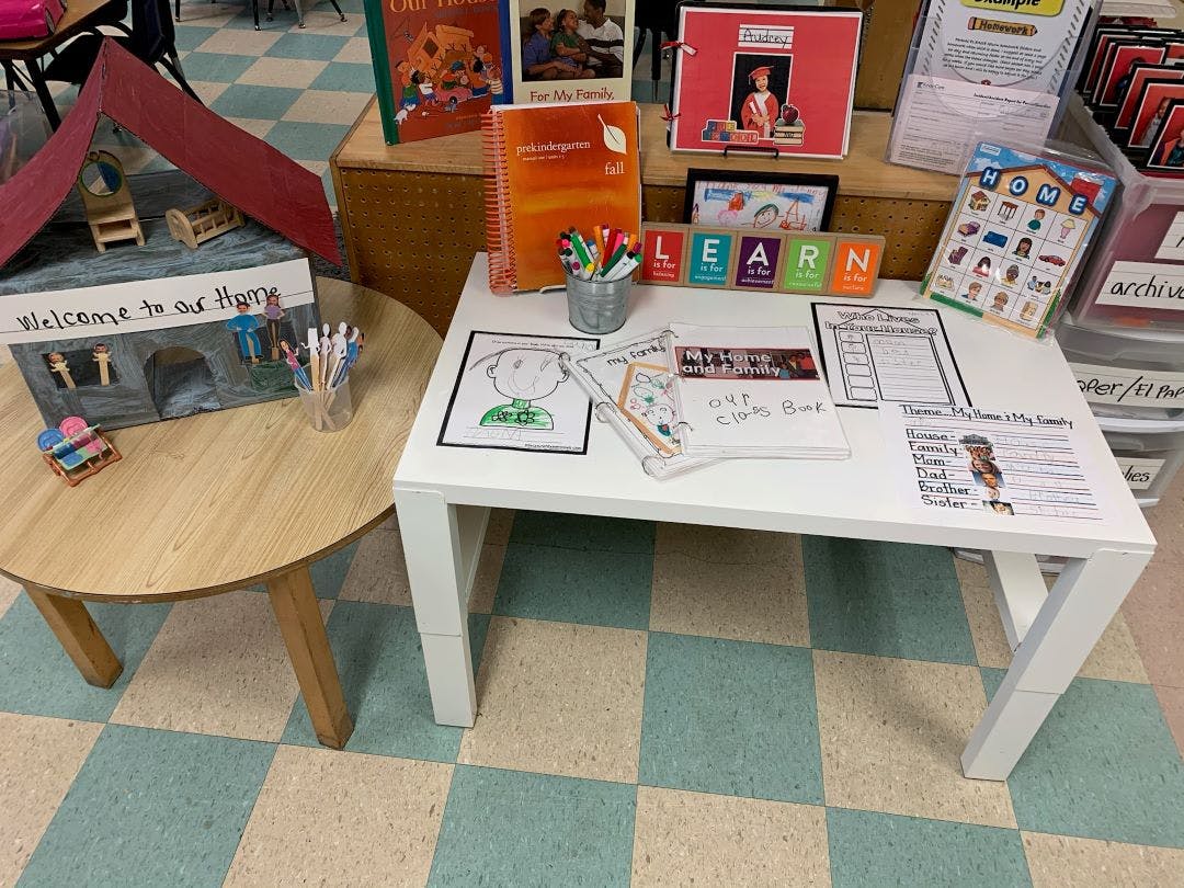 Classroom display with a cardboard house, books, and children's activity sheets