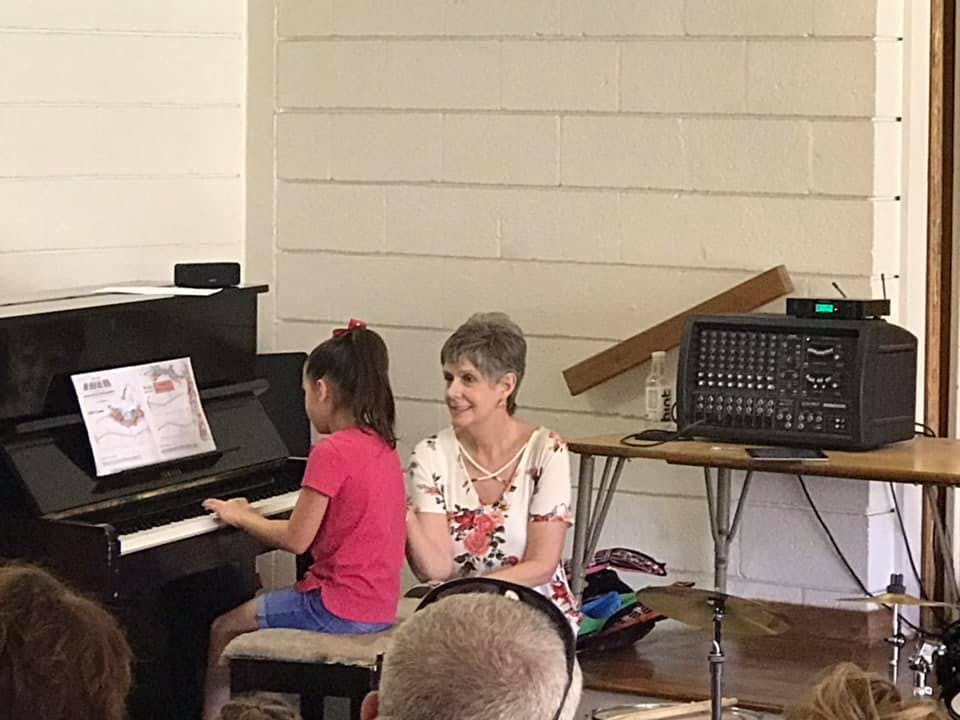 Child playing piano with an adult sitting next to them