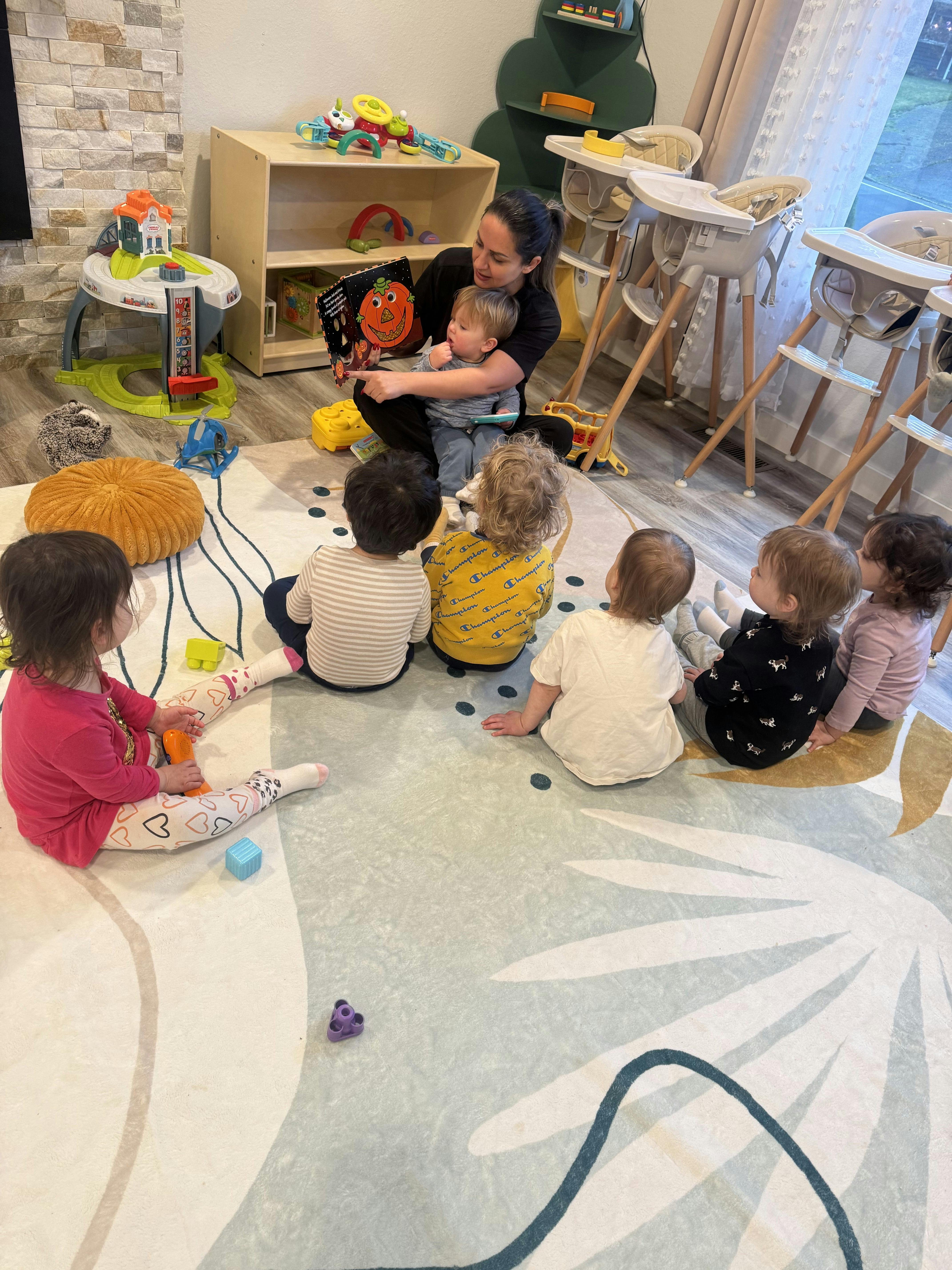 person holding a book with a pumpkin on it, reading to young children