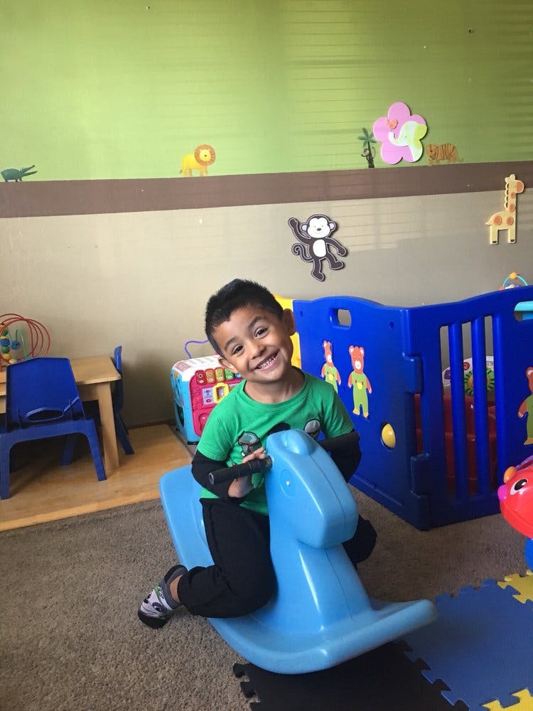 Child on a blue rocking horse in a play area