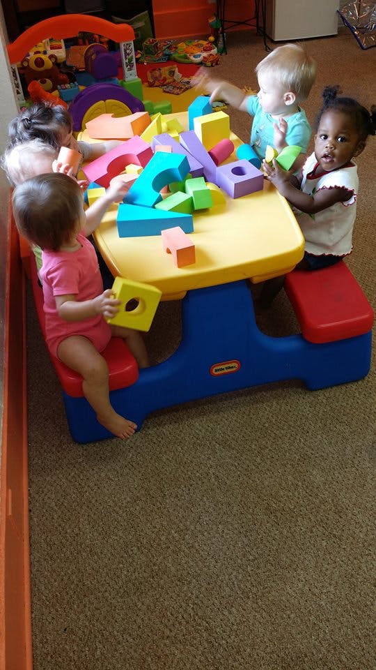 Children playing with colorful building blocks at a small table