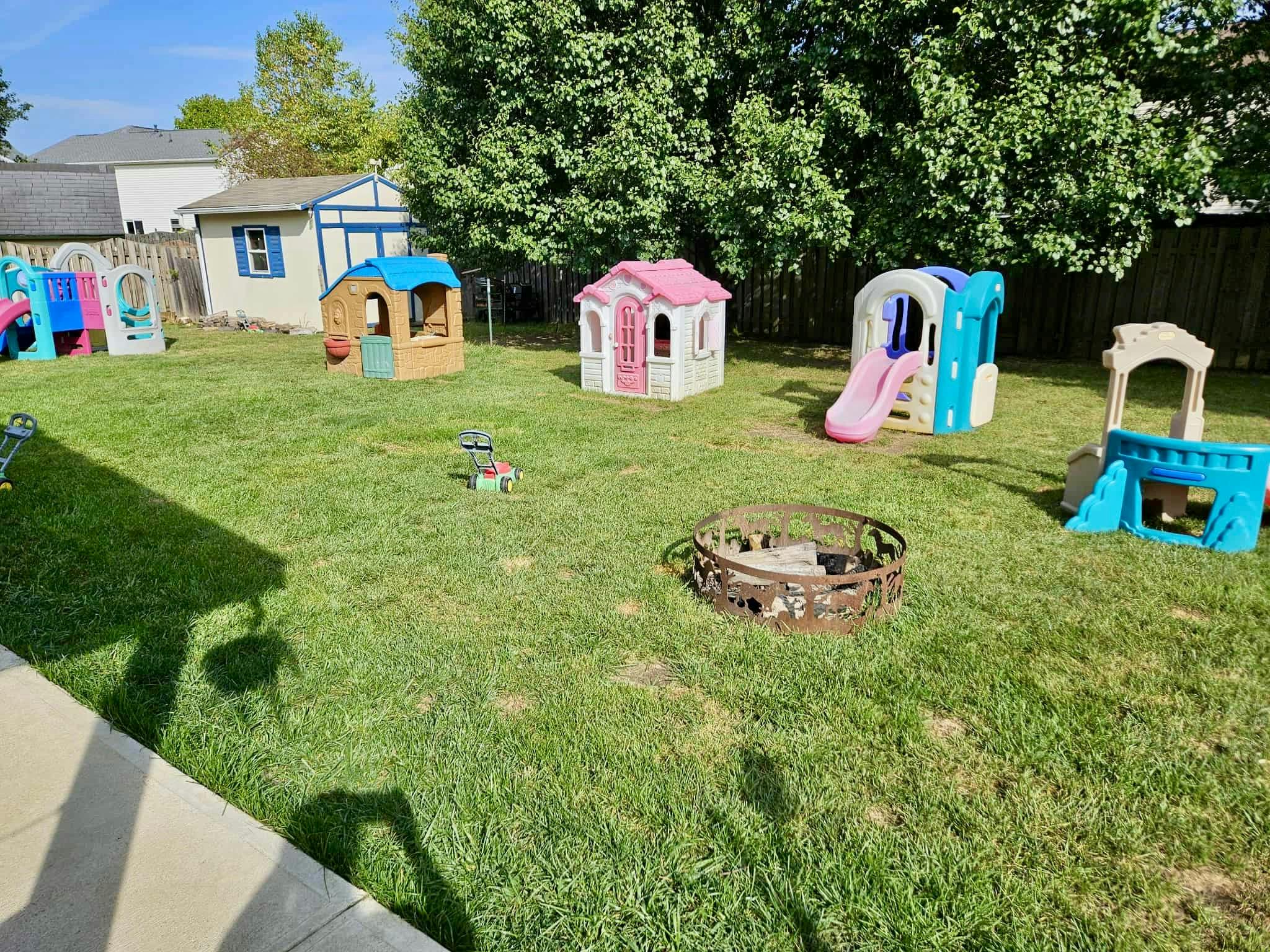 Backyard with multiple playhouses, slides, and a fire pit