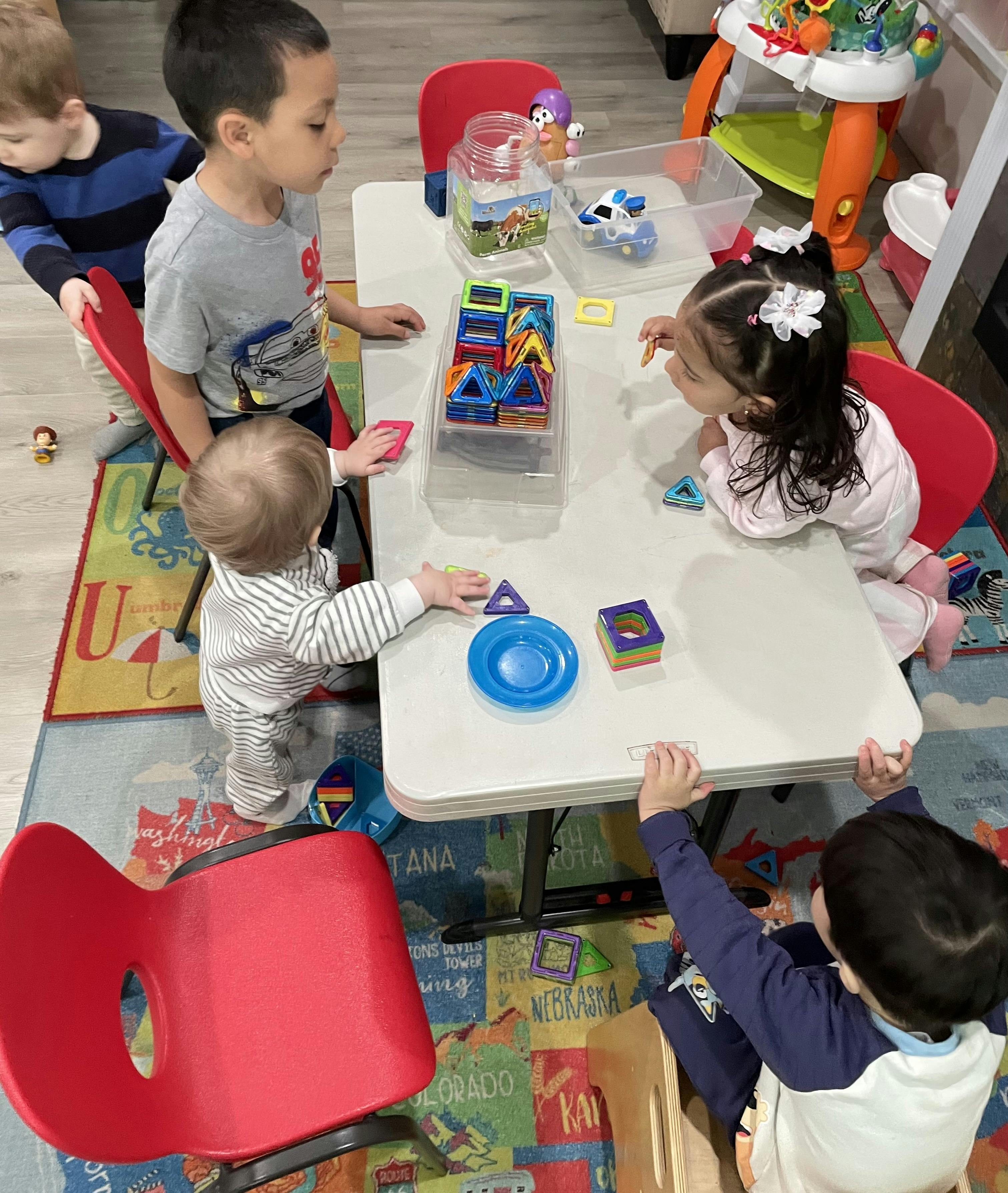 multiple children playing with colorful magnetic tiles at a table