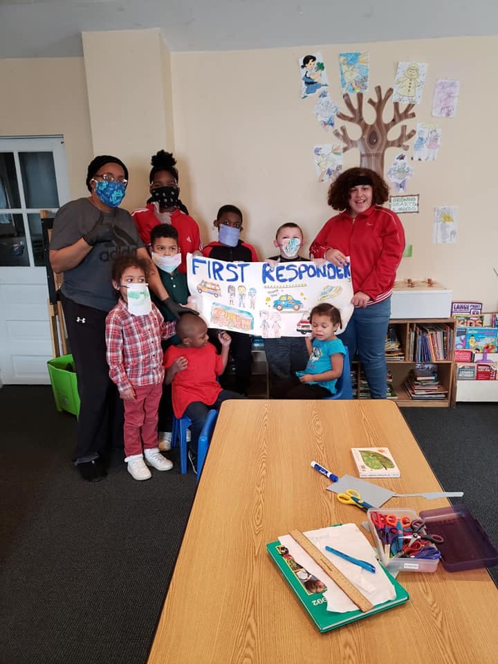 Group of people and children holding a sign that says "FIRST RESPONDER"