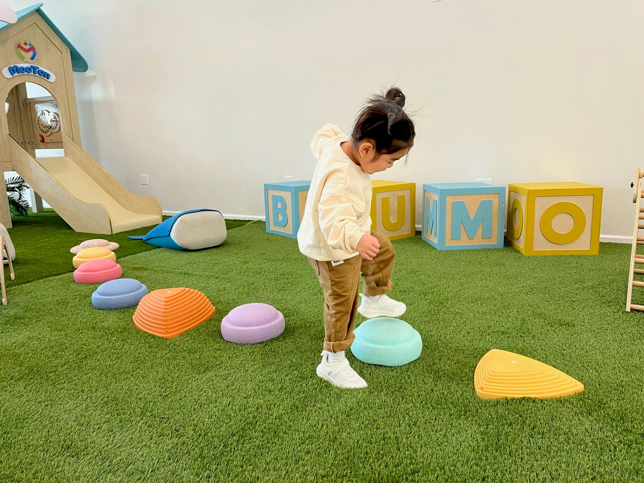 Child stepping on colorful balance stones on artificial grass