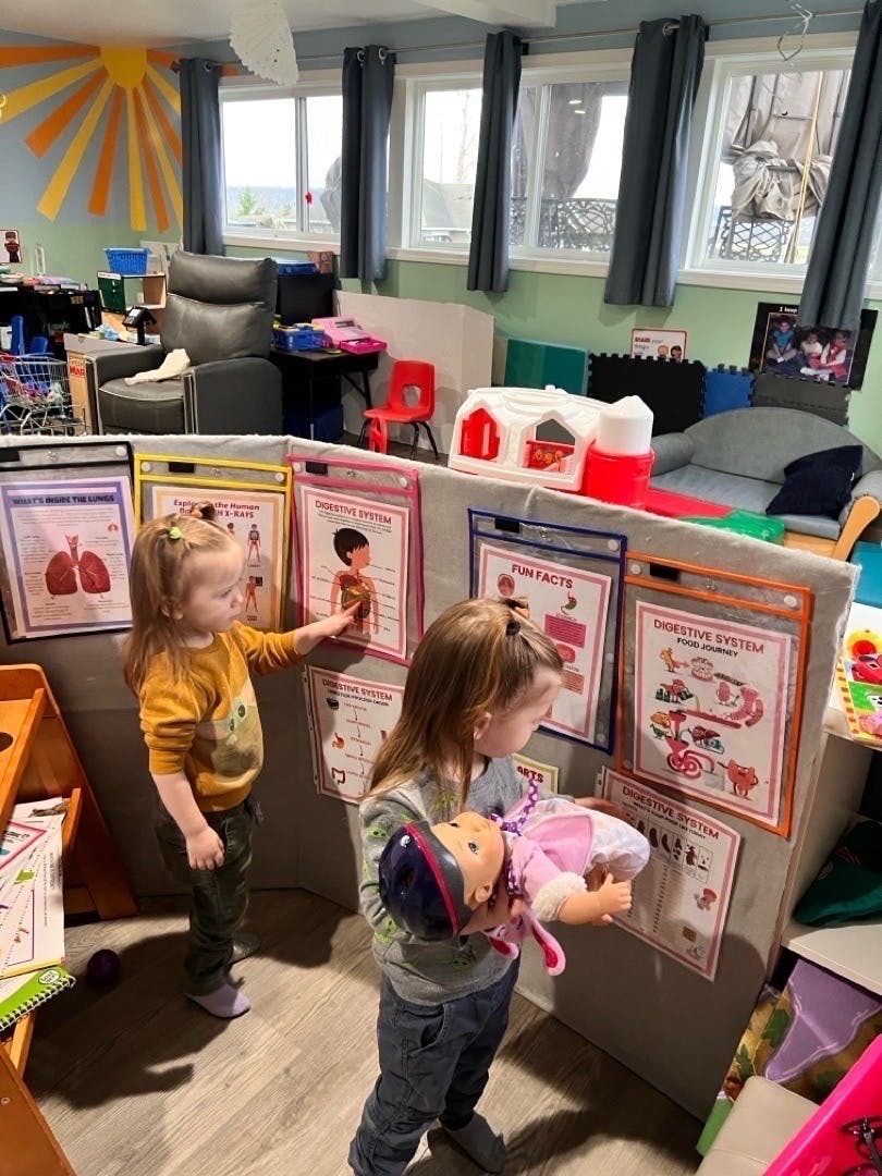 Two children looking at posters in a classroom setting
