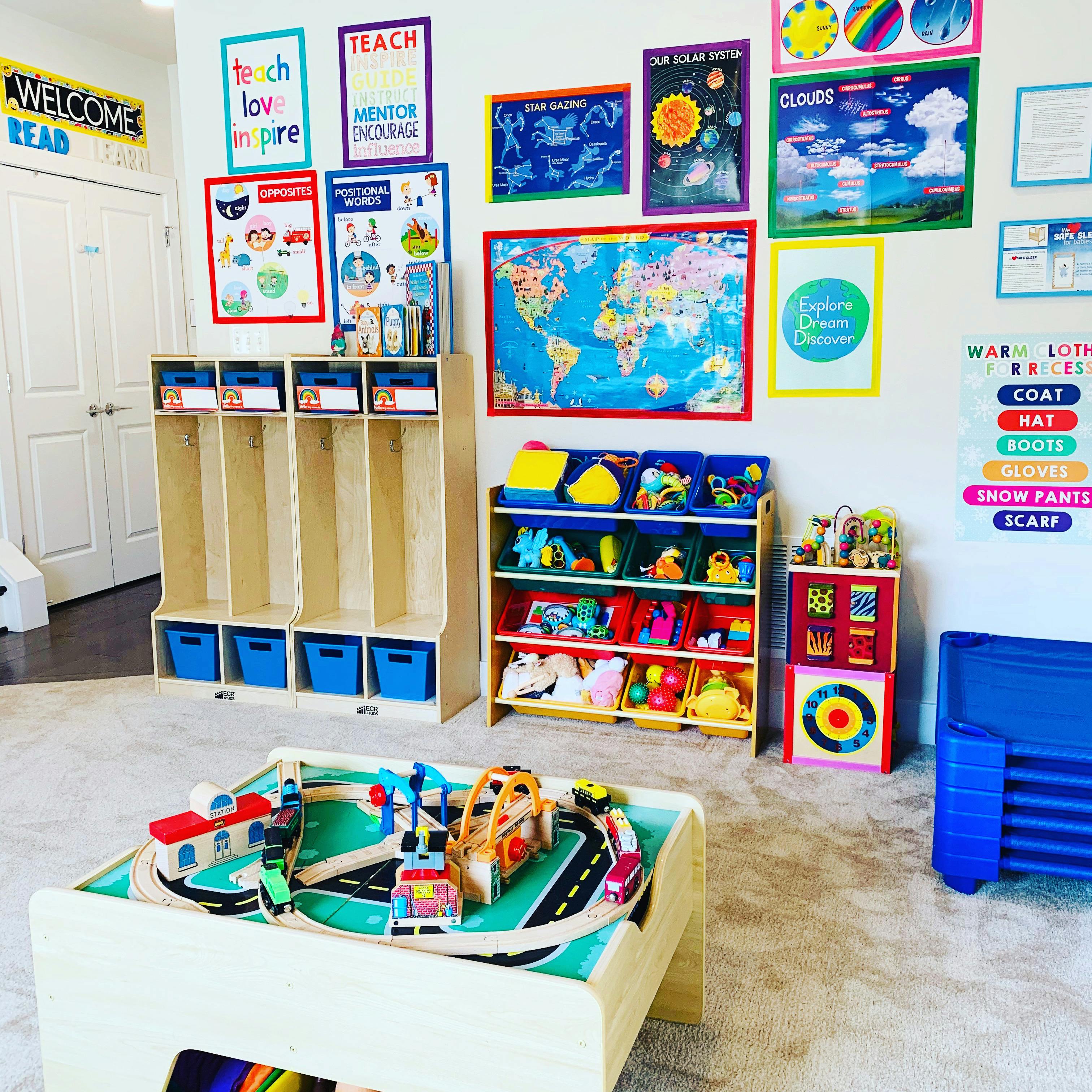 Classroom with cubbies, toy shelves, and a play table with a train set