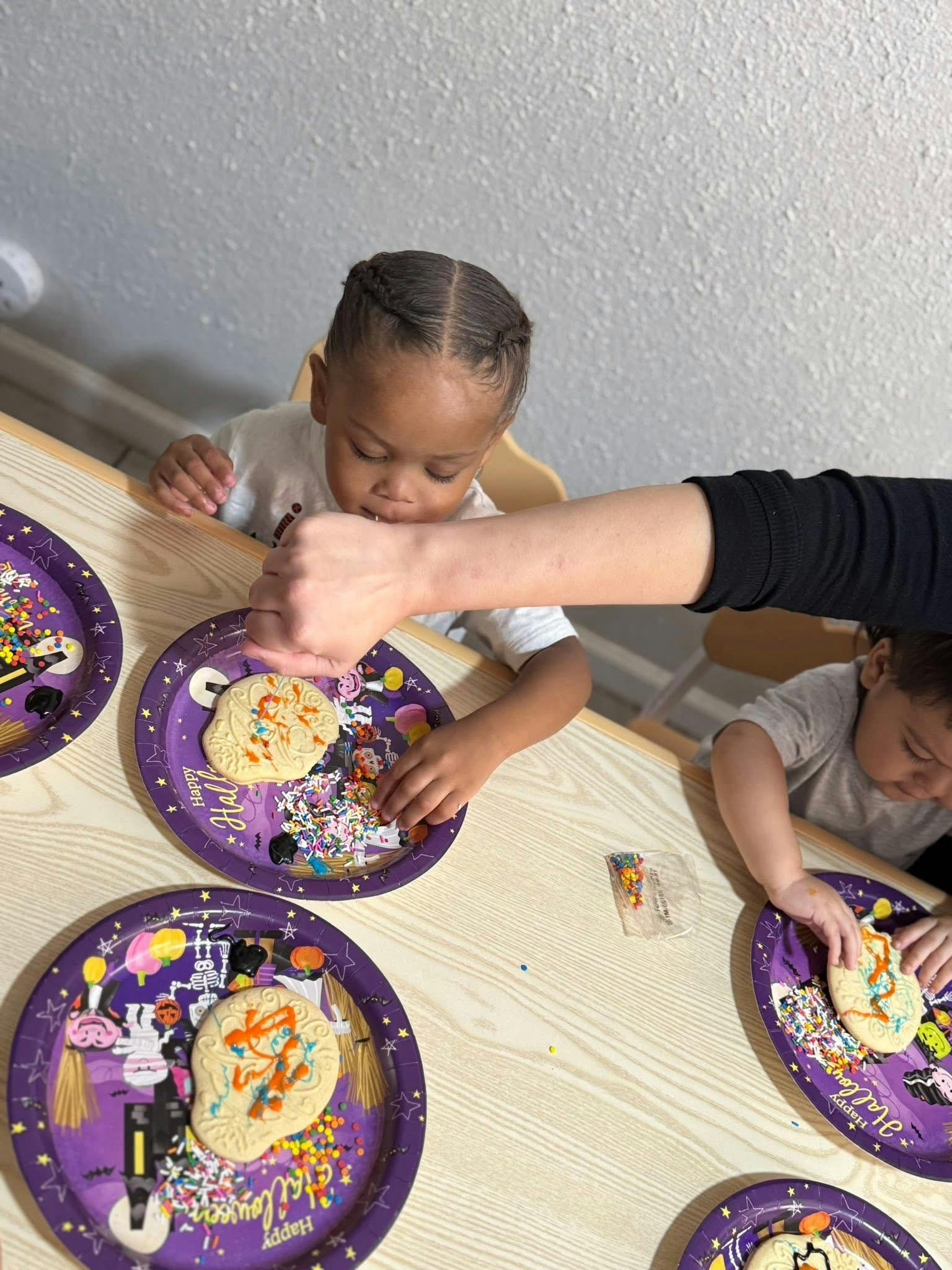 People decorating Halloween cookies on festive plates at a table