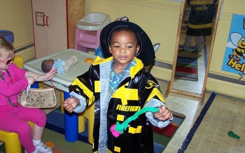 Child in firefighter costume holding a toy