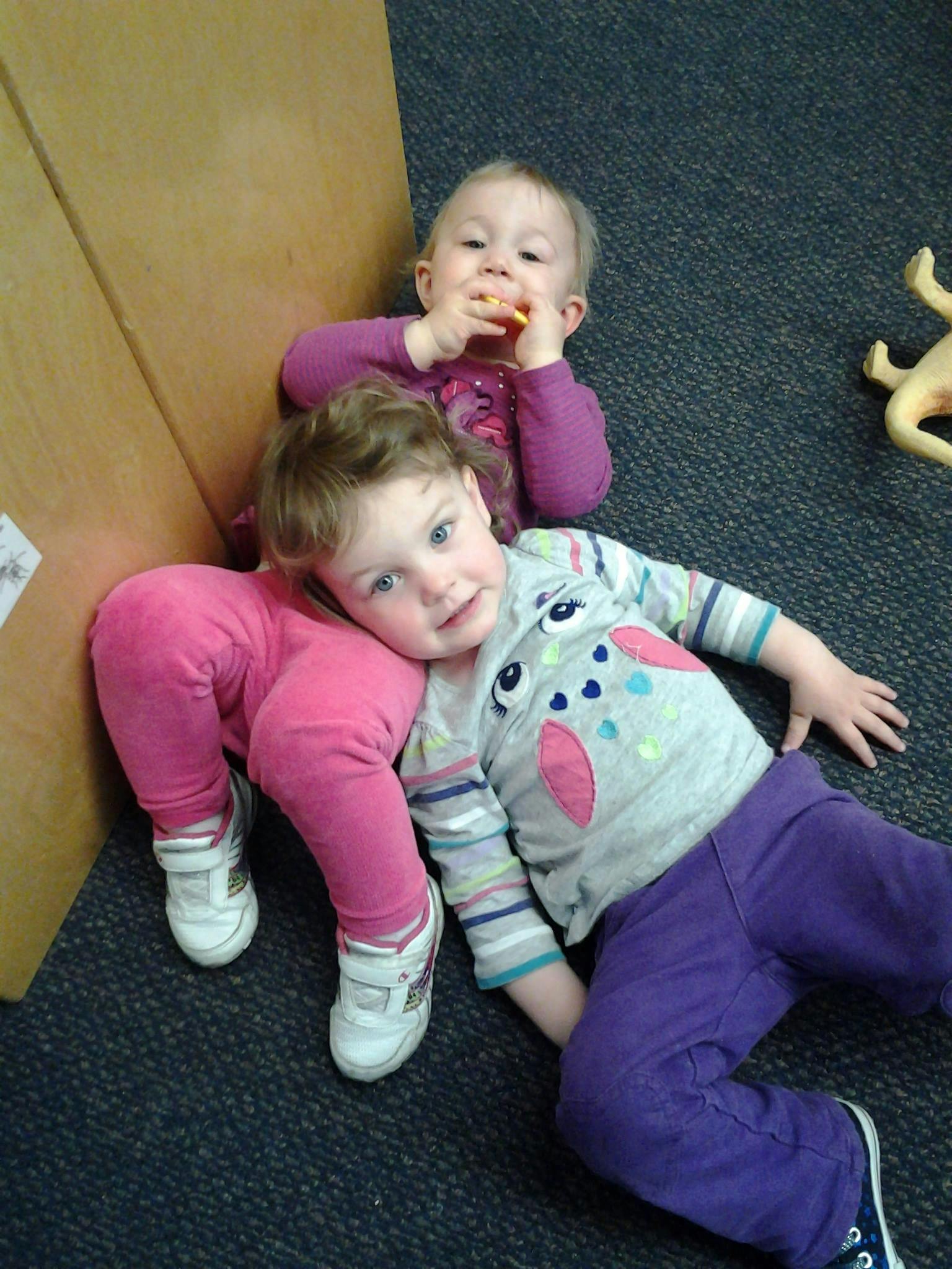 Two children on the floor, one eating a snack