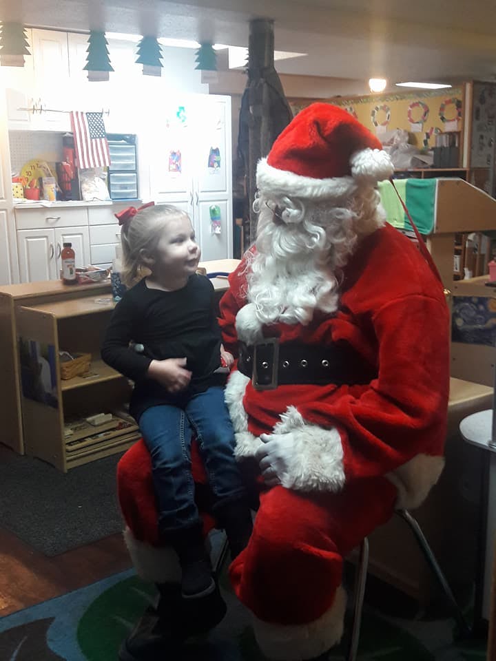 Child sitting on a person dressed as Santa Claus