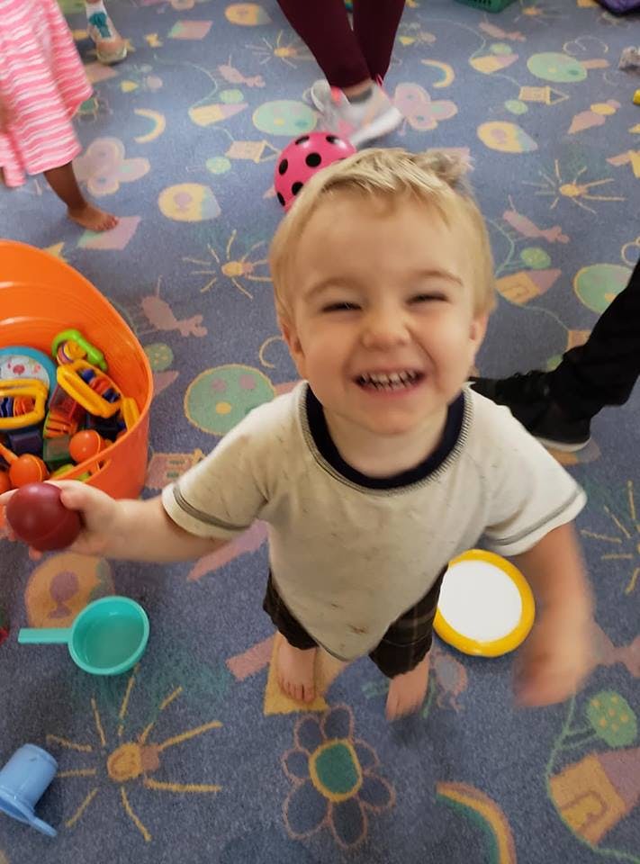 Child holding a red toy, smiling