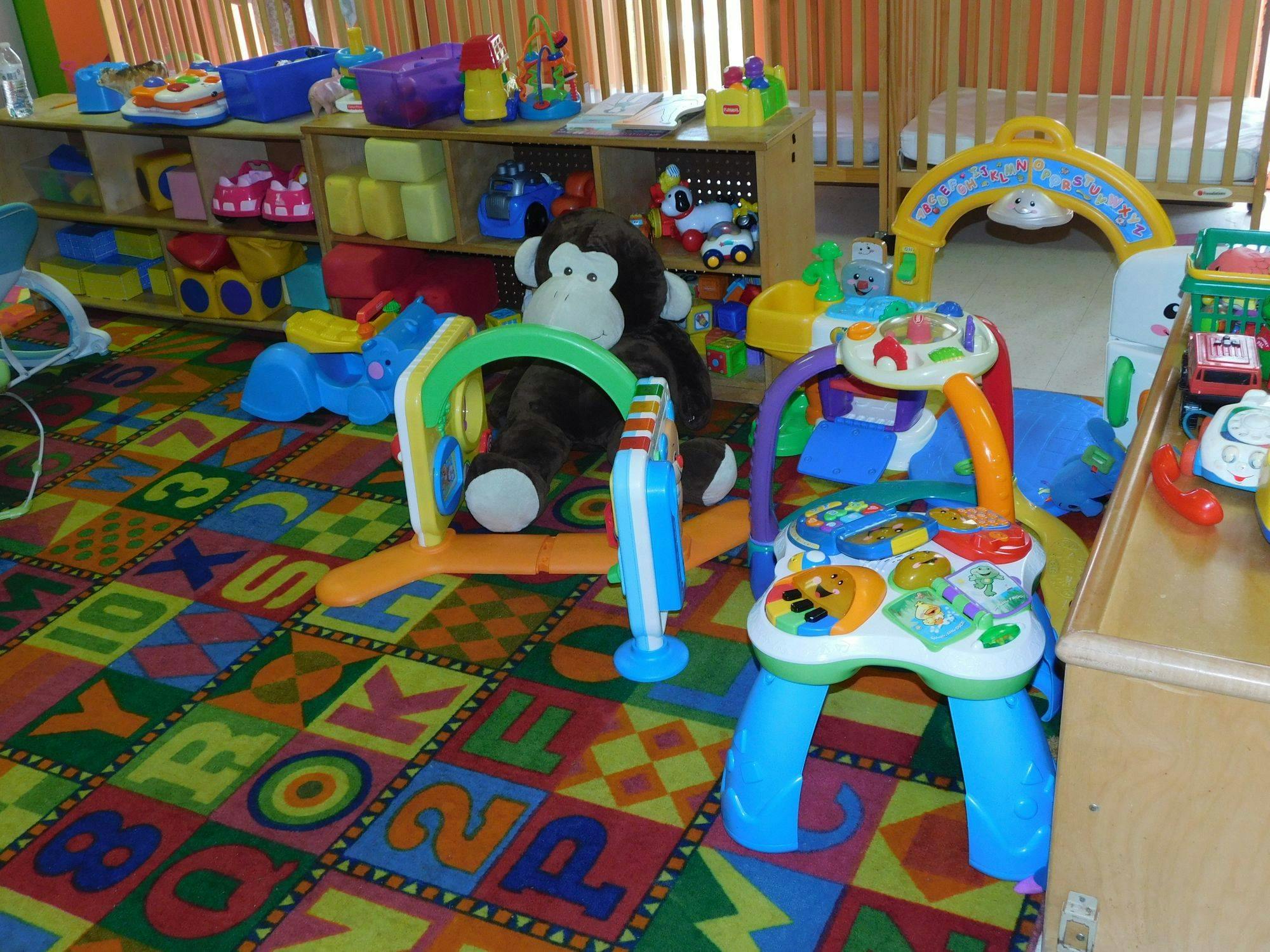 Playroom with colorful alphabet rug, toys, and stuffed monkey
