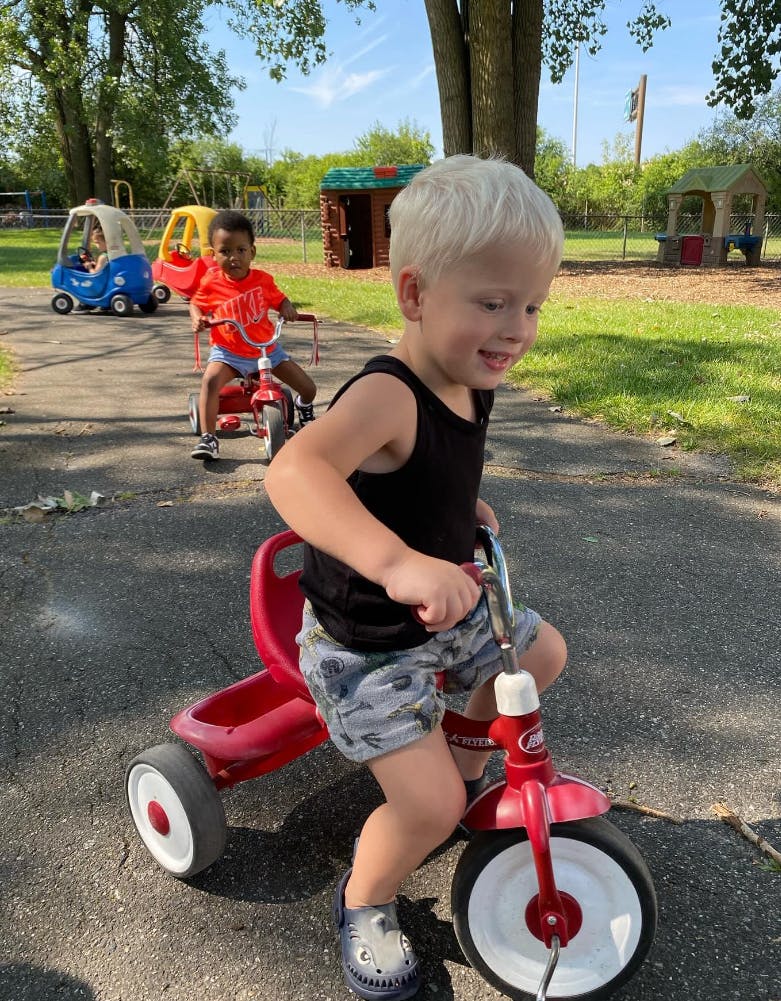 Children riding tricycles and toy cars outdoors