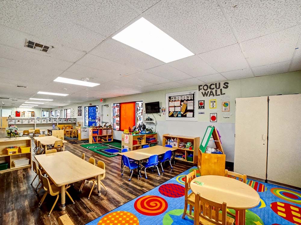 Empty classroom with small tables, chairs, and learning materials