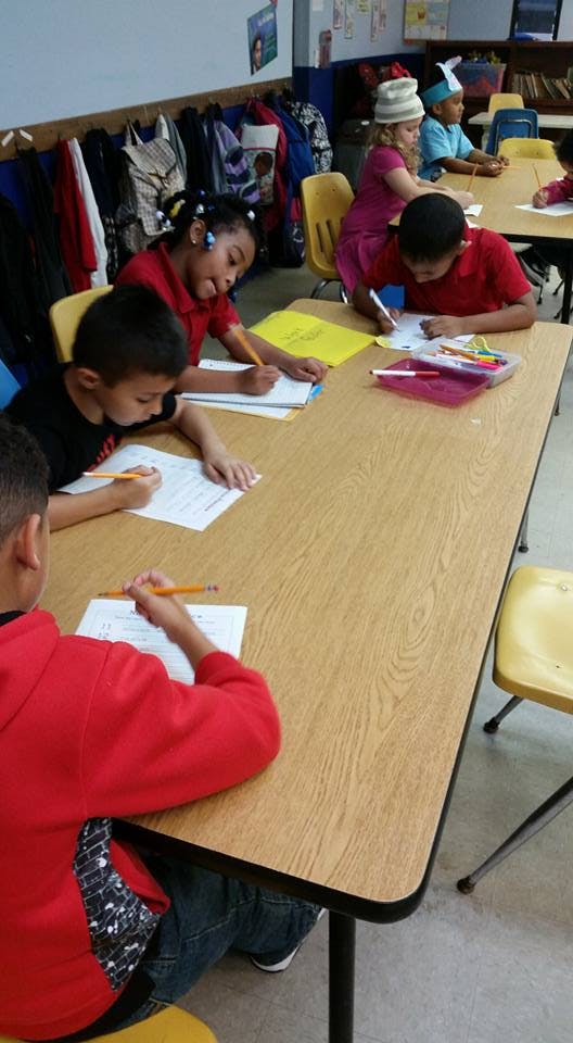 Children writing at desks in a classroom
