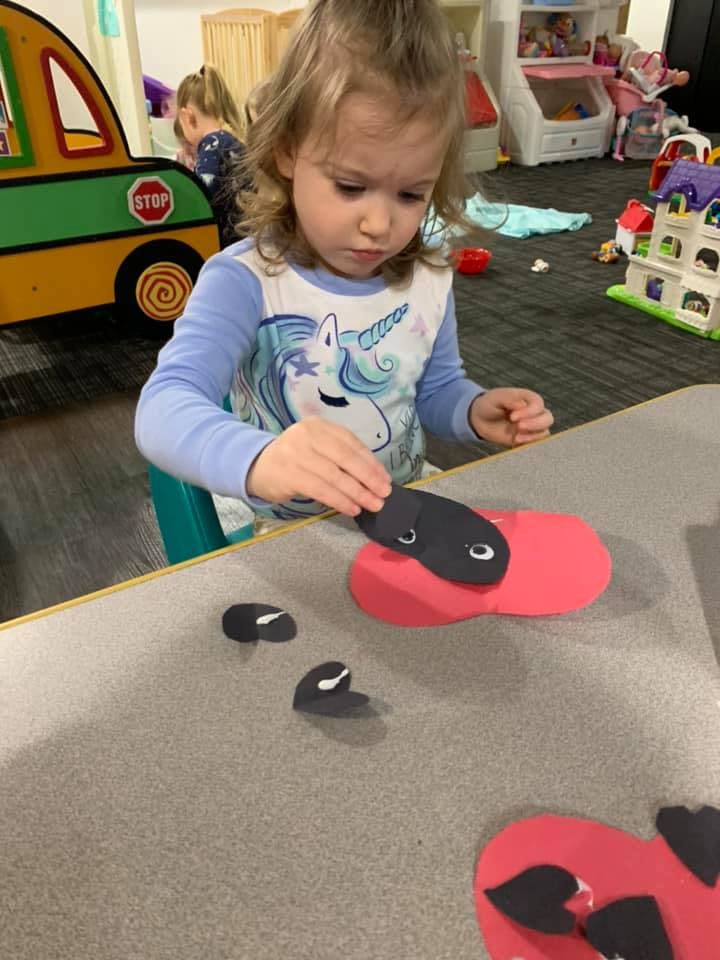 Child making a craft with red and black paper cutouts