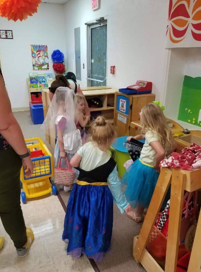 Children playing in a classroom with dress-up clothes and toys