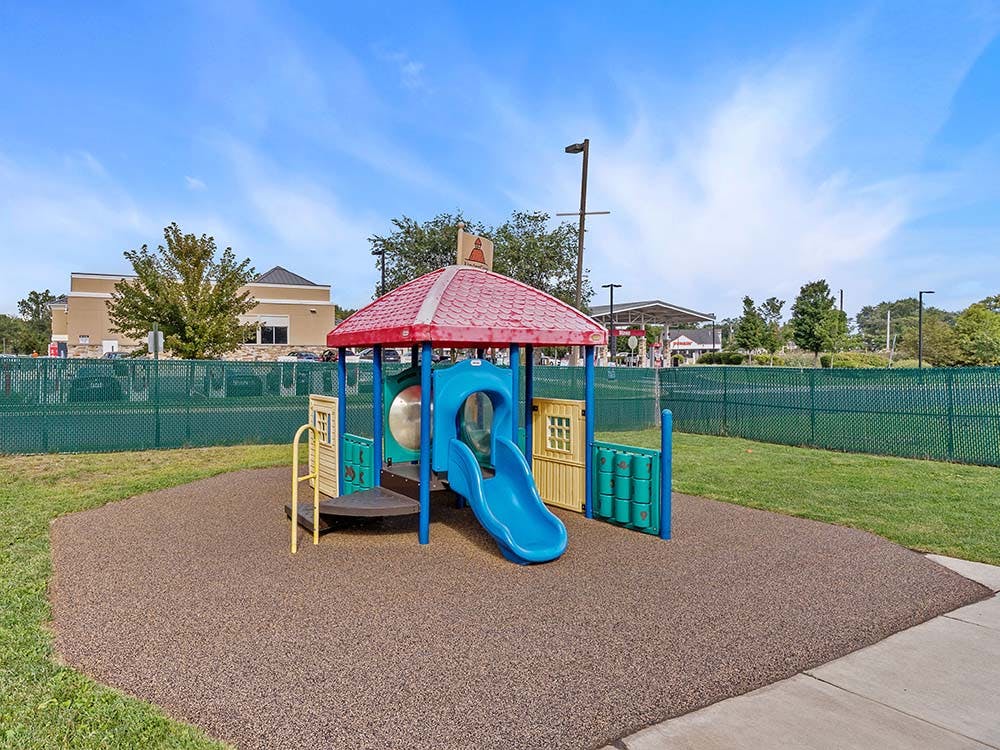 Colorful playground structure with a blue slide on a brown soft surface