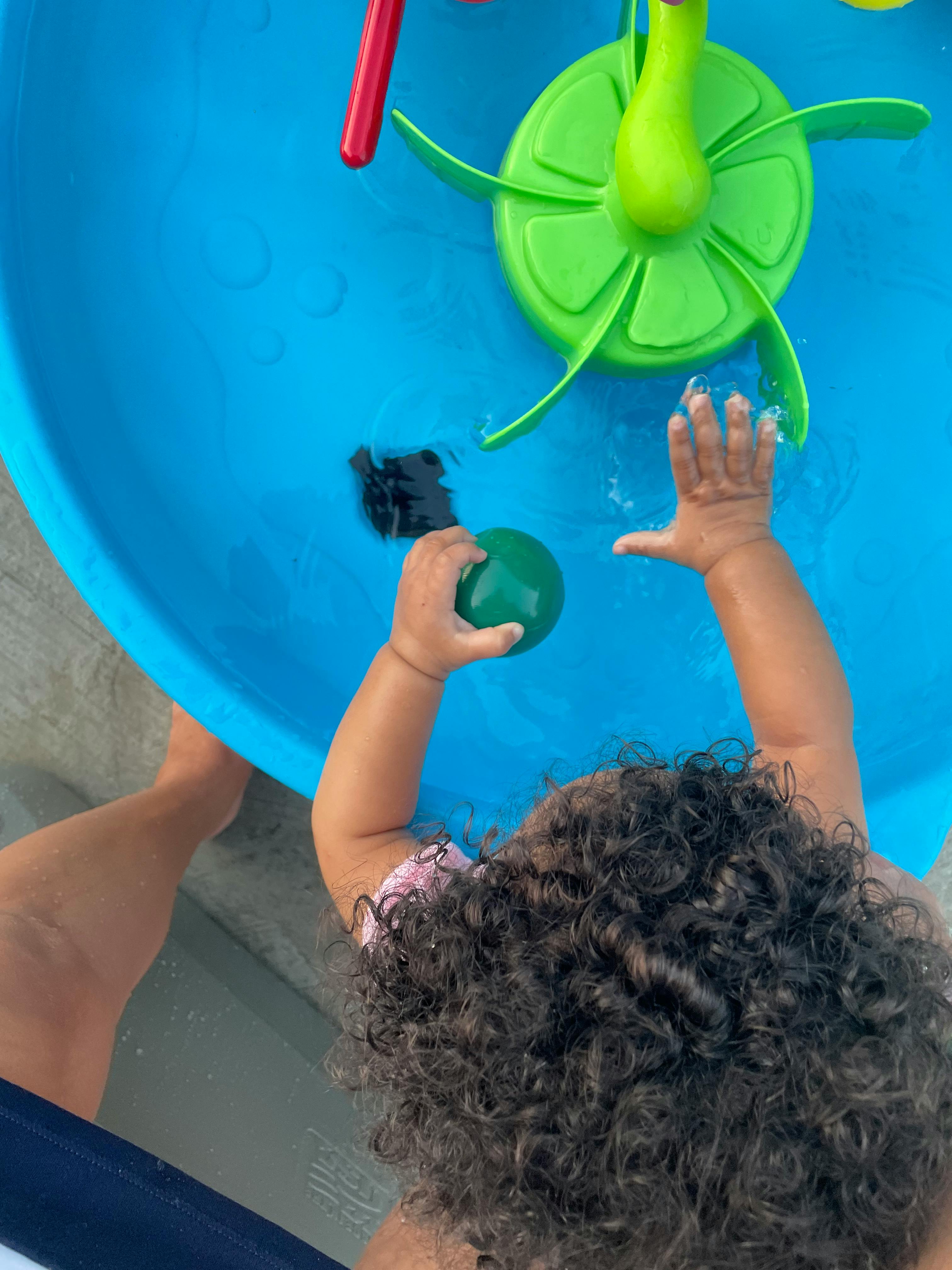 Child playing with water in a blue basin