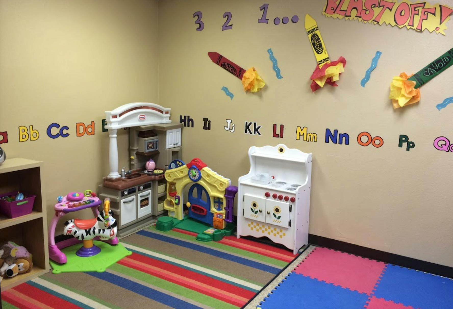 Playroom with toy kitchen, playhouse, and alphabet letters on the wall