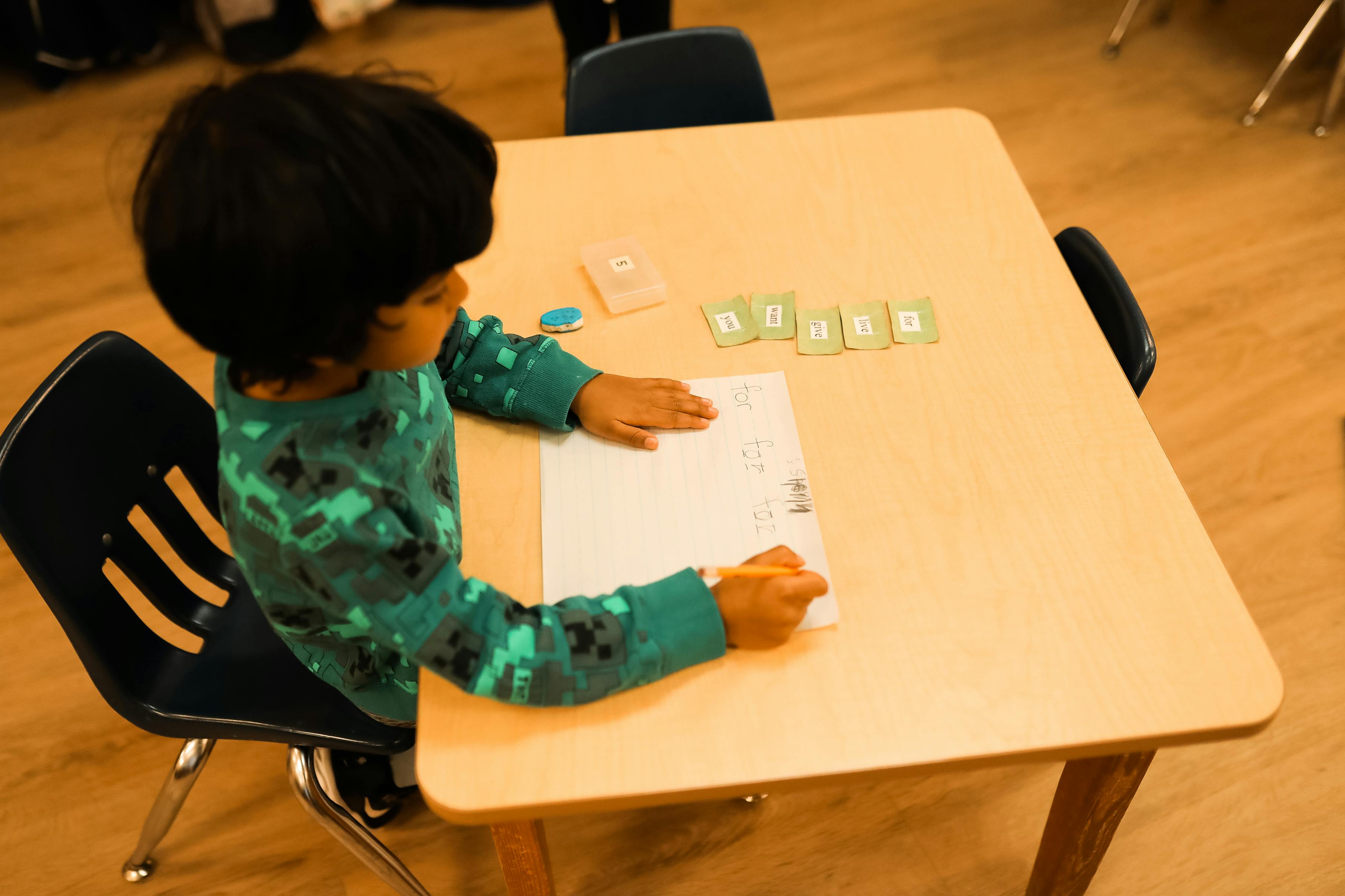 Child sitting at a table writing on paper